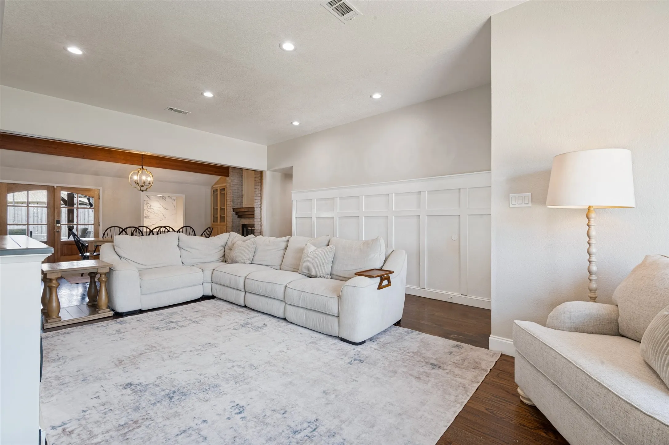 Living room with recessed lighting, wood flooring, board and batten wainscoting paneling, and an open-concept layout