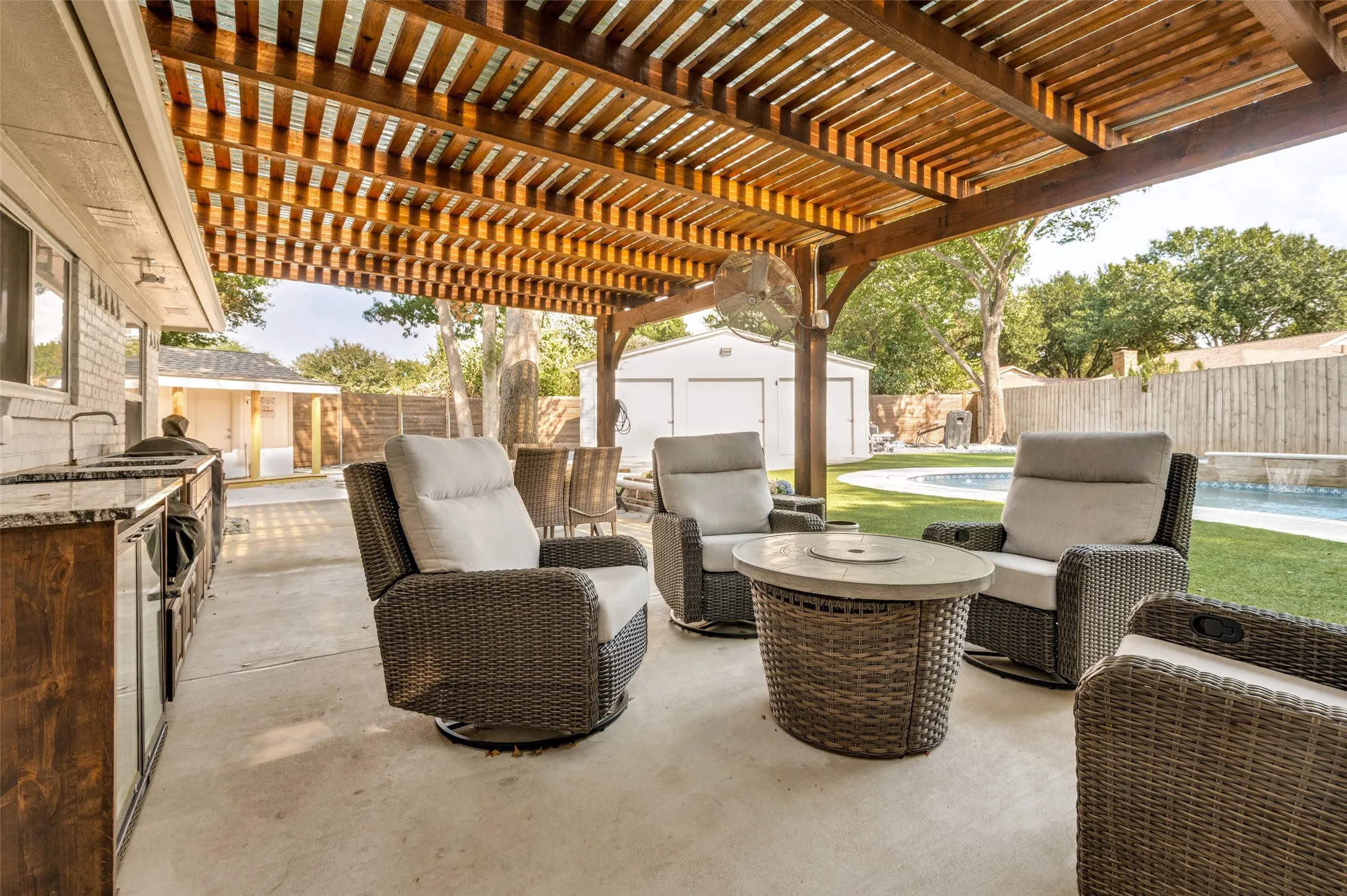 Patio with a wood pergola, built-in outdoor kitchen with a sink, refrigerator, granite countertops, custom cabinetry, and a swimming pool