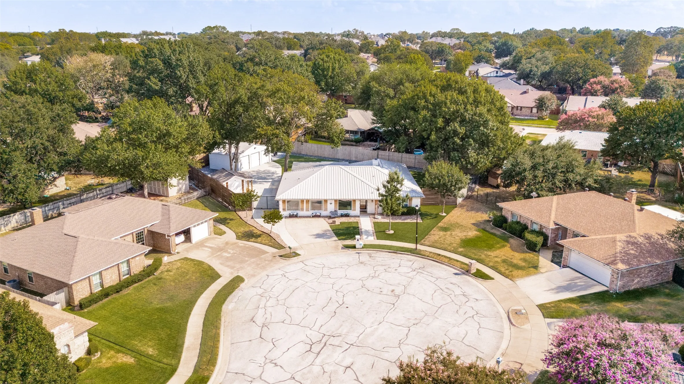 Single-story residence in a cul-del-sac with a metal roof, flex room, 3 car garage and mature landscaping