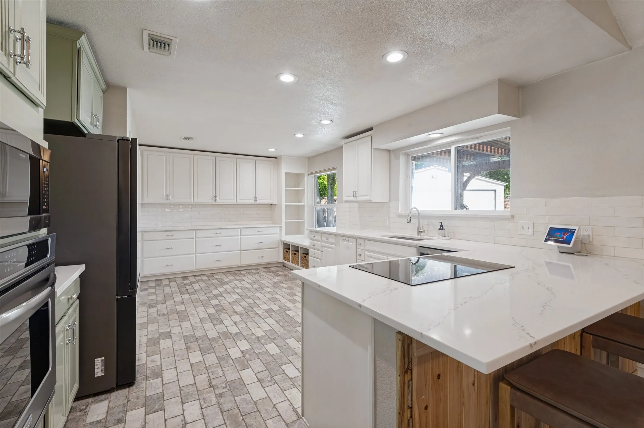 Kitchen featuring white quartz countertops, stainless steel appliances, custom cabinetry