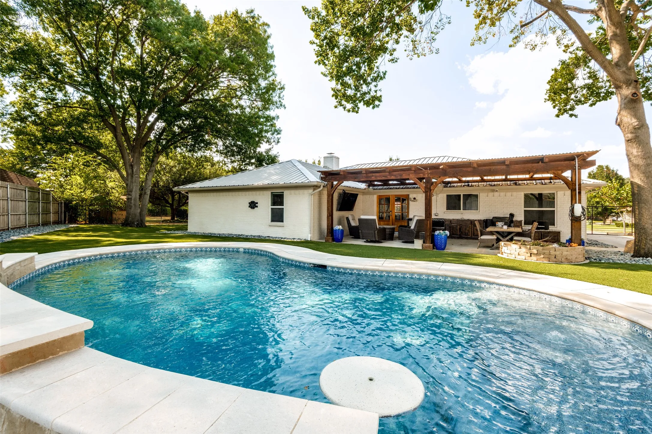 Beautiful swimming pool, an expansive covered patio featuring a built-in outdoor kitchen, and a separate stone-clad fire pit