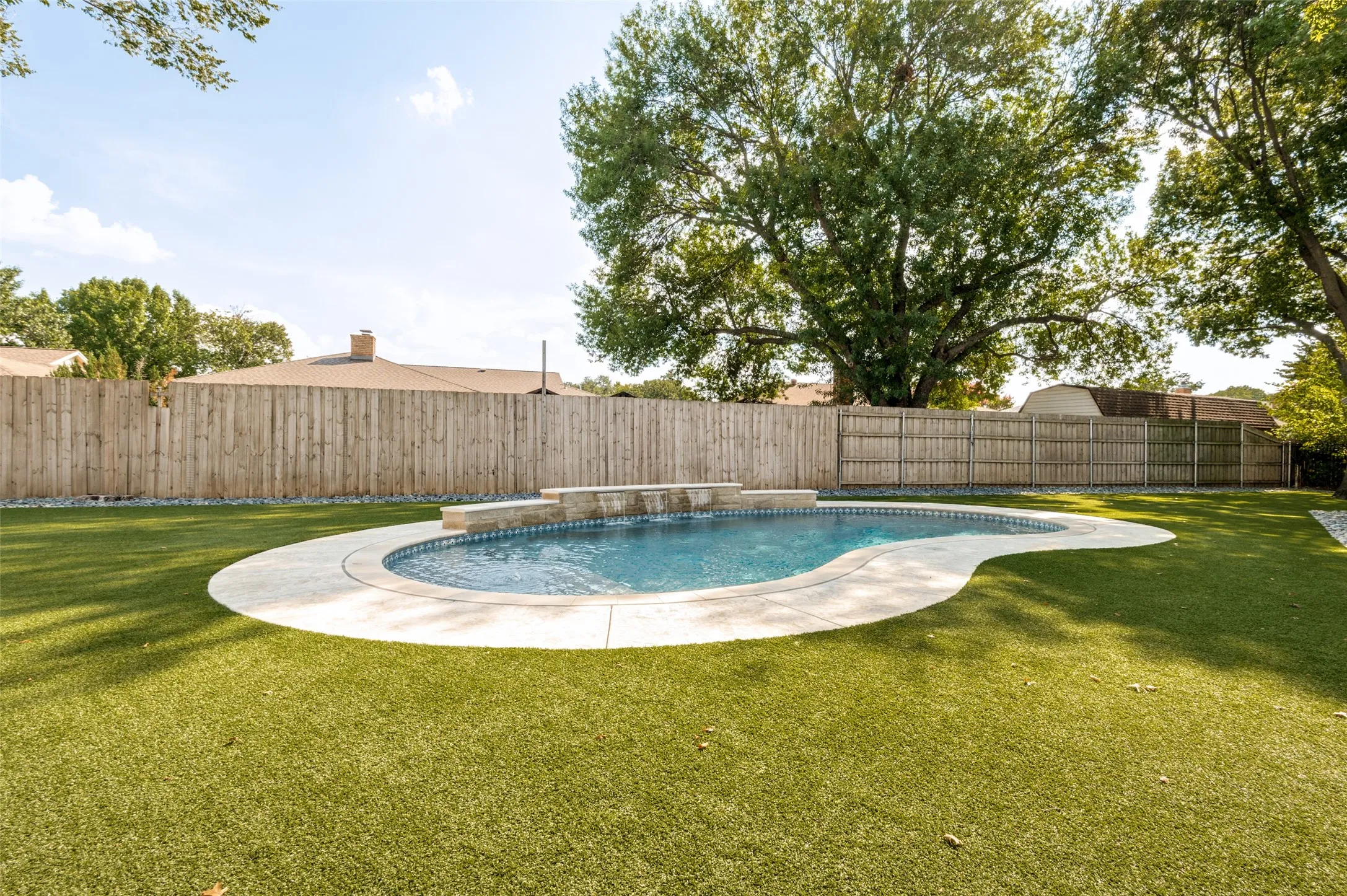 Freeform swimming pool with a triple cascading rock waterfall feature