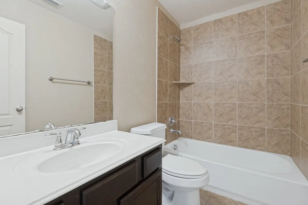 Bathroom featuring a vanity with an integrated sink, polished chrome faucet, dark wood-finish cabinetry, and a full-width mirror