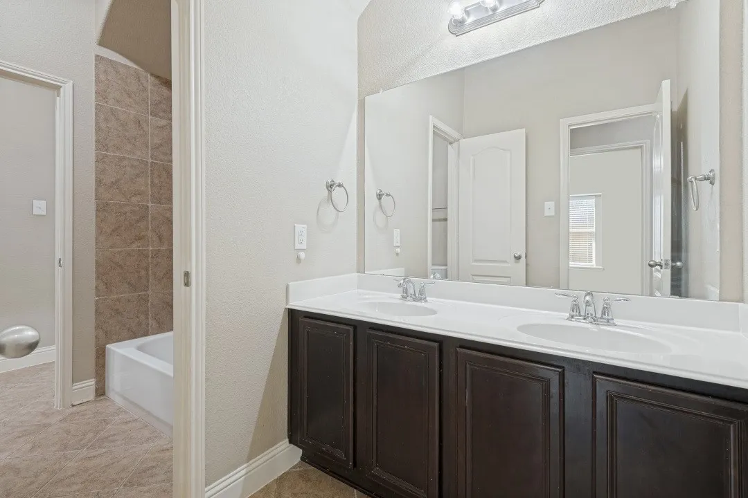 Dual vanity with integrated sinks, dark wood-finish cabinetry, and a full-width mirror