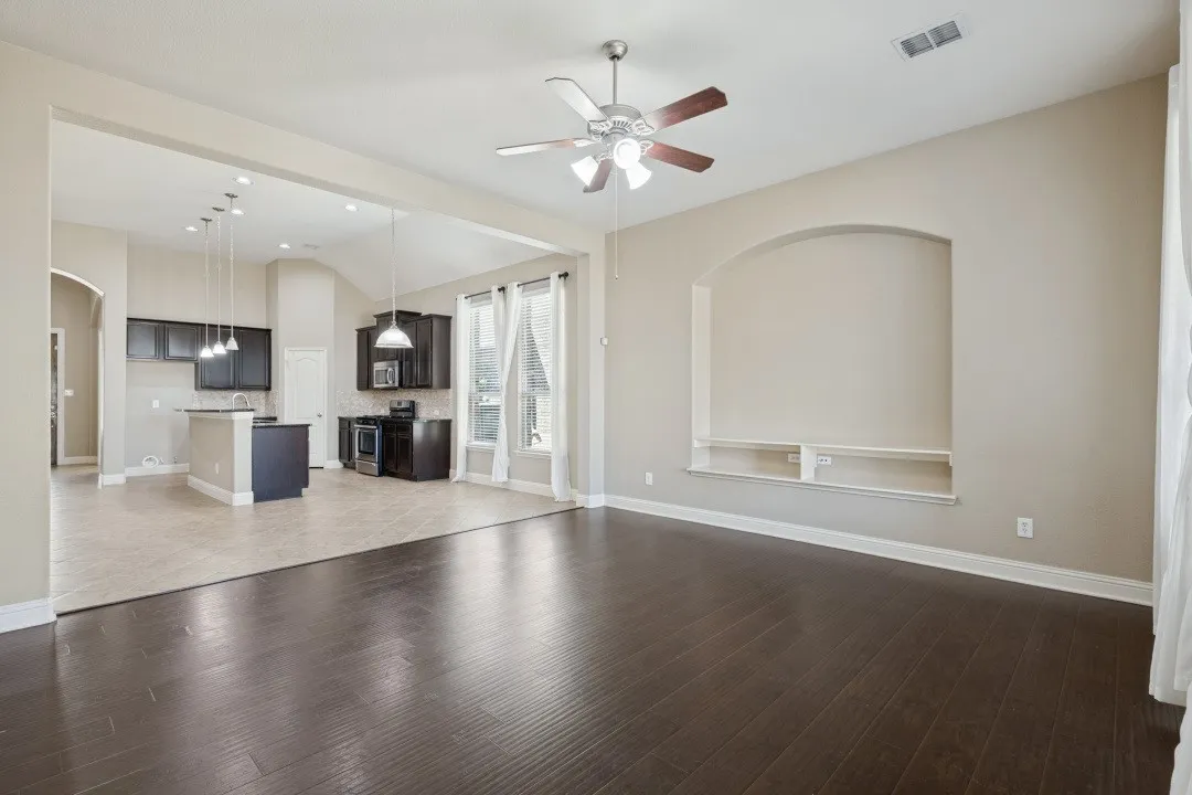 Wood-finish flooring, recessed wall niche with shelving, and a ceiling fan