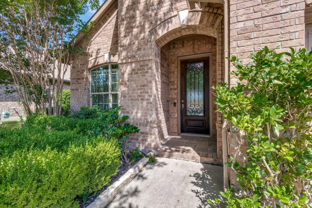 Brick exterior featuring an arched entryway, decorative glass front door, and a curved window with louvered blinds