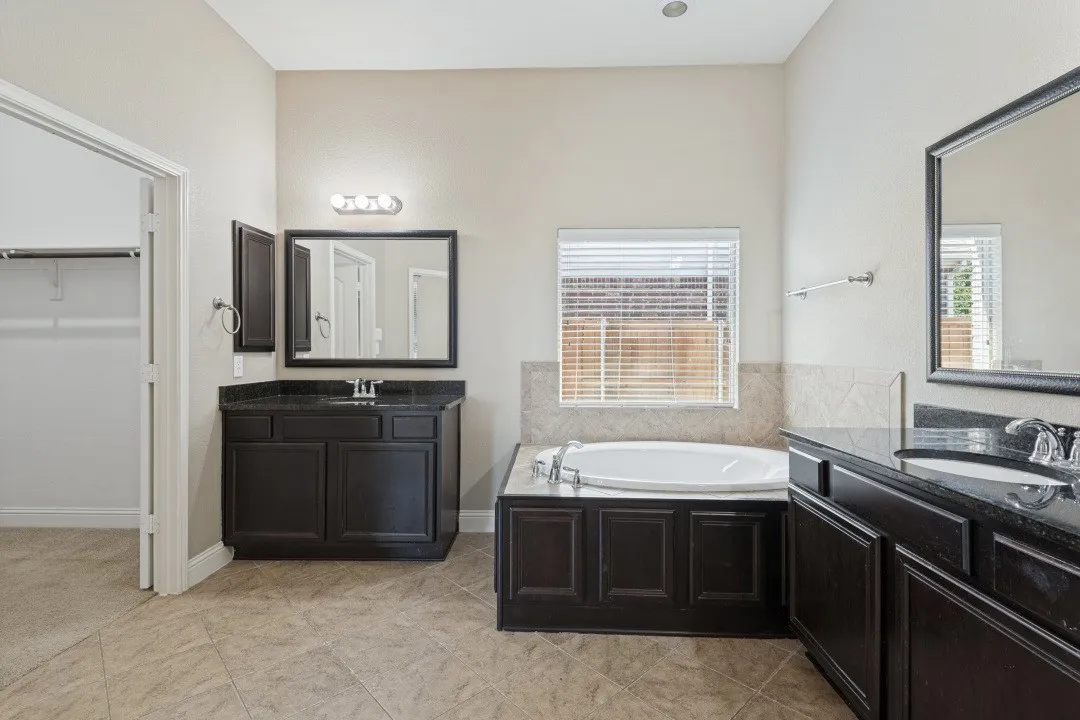 Dual vanities with dark cabinetry and stone countertops. All bathrooms in the home are oversized.