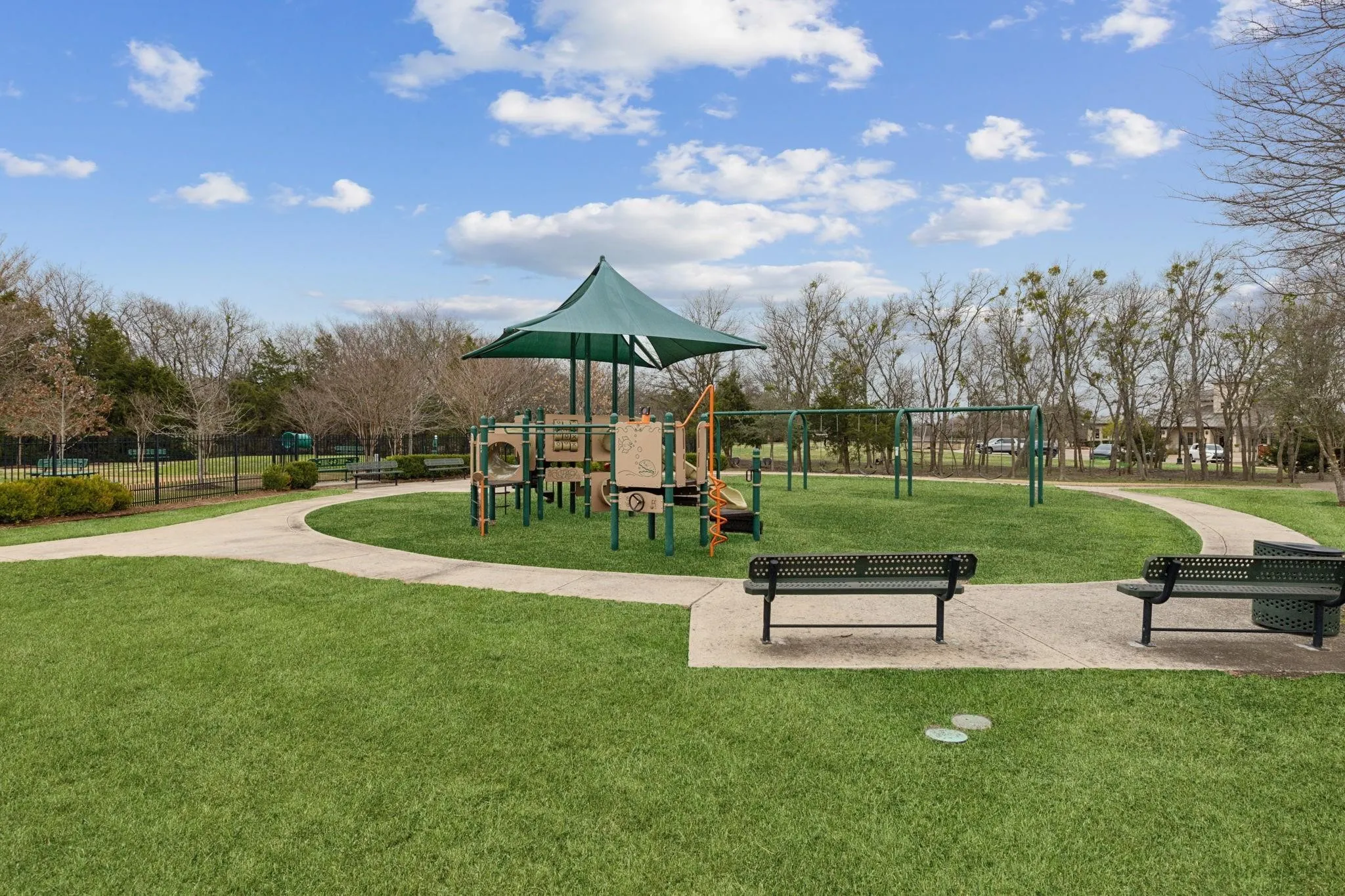 Community park with a playground, swings, paved walking paths, and green space