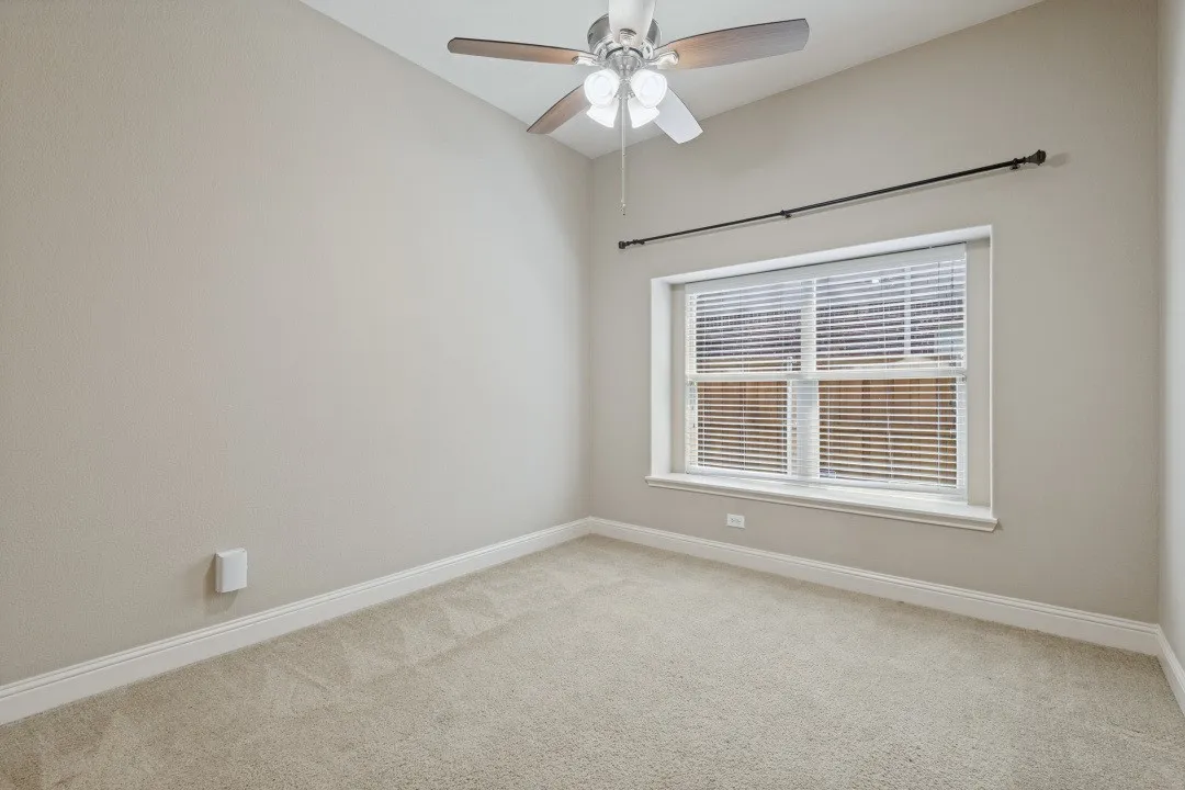 Vaulted ceiling with a ceiling fan, neutral carpeting, and a window with blinds