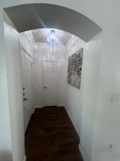 Arched entryway with paneled doors, and a decorative crystal light fixture