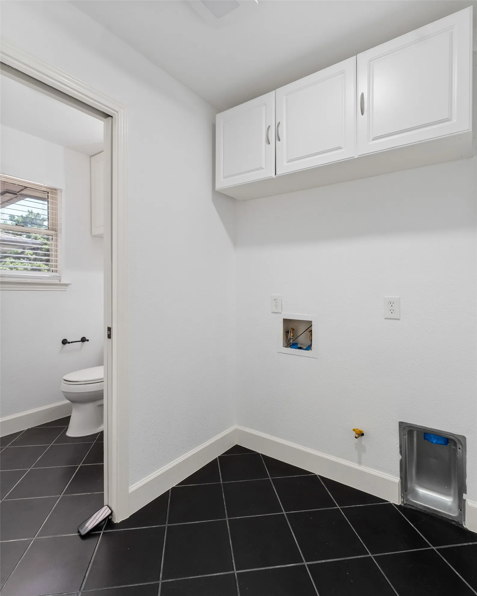 White cabinetry with silver-tone pulls, dark square tile flooring, and white baseboards