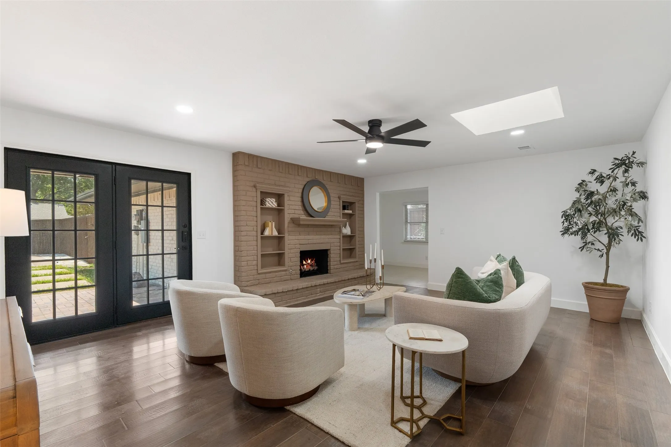 Brick fireplace with built-in shelving, wood-finish flooring, recessed lighting, ceiling fan, and French doors