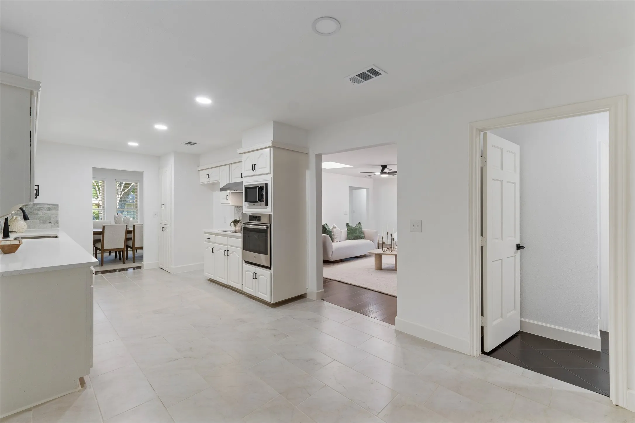 White cabinetry with stainless steel appliances, recessed lighting, and light-toned flooring