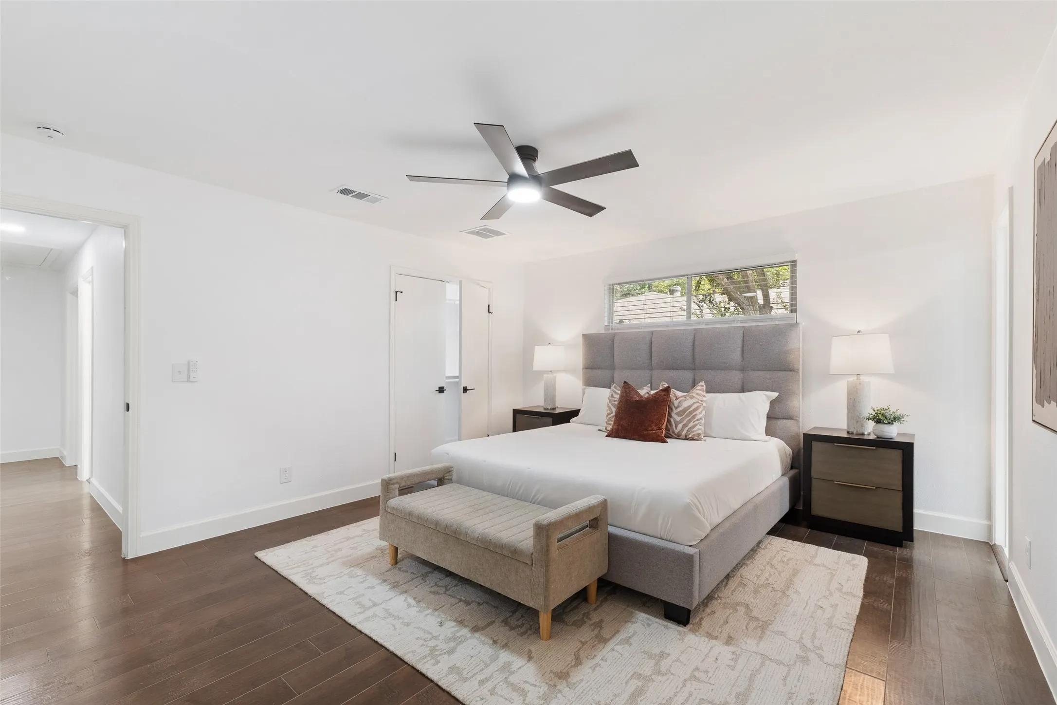 Spacious room featuring wood-finish flooring, a contemporary ceiling fan, and white walls