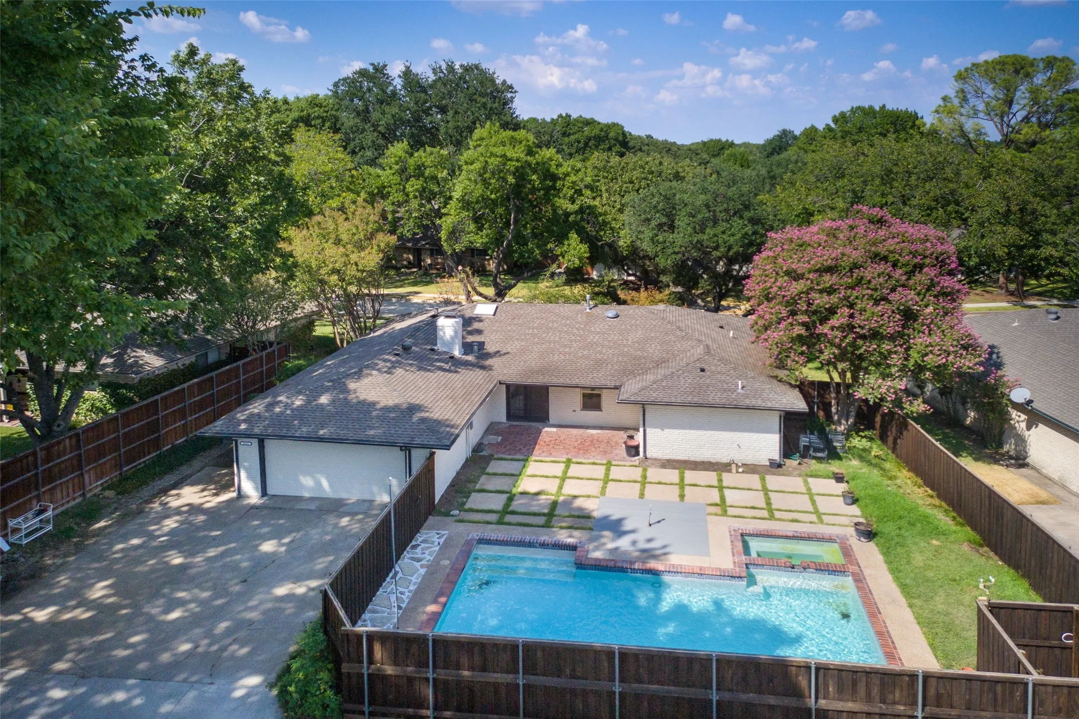 White exterior with a shingle roof, a swimming pool, and a spa