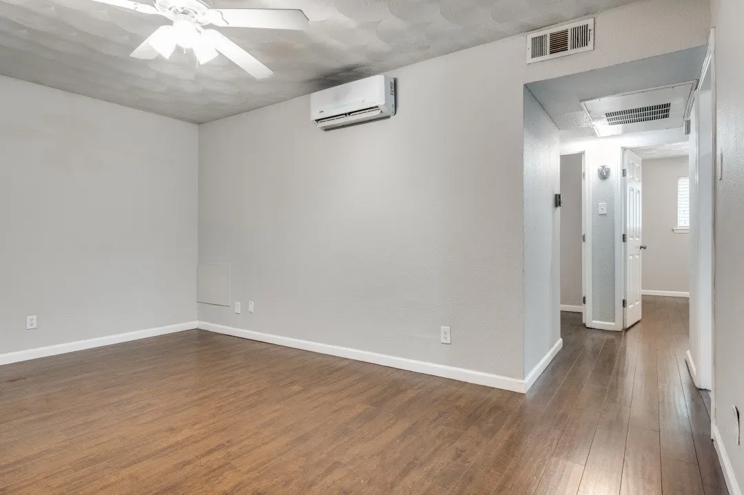 Wood-finish flooring, ceiling fan, split-system air conditioning unit, and white baseboards