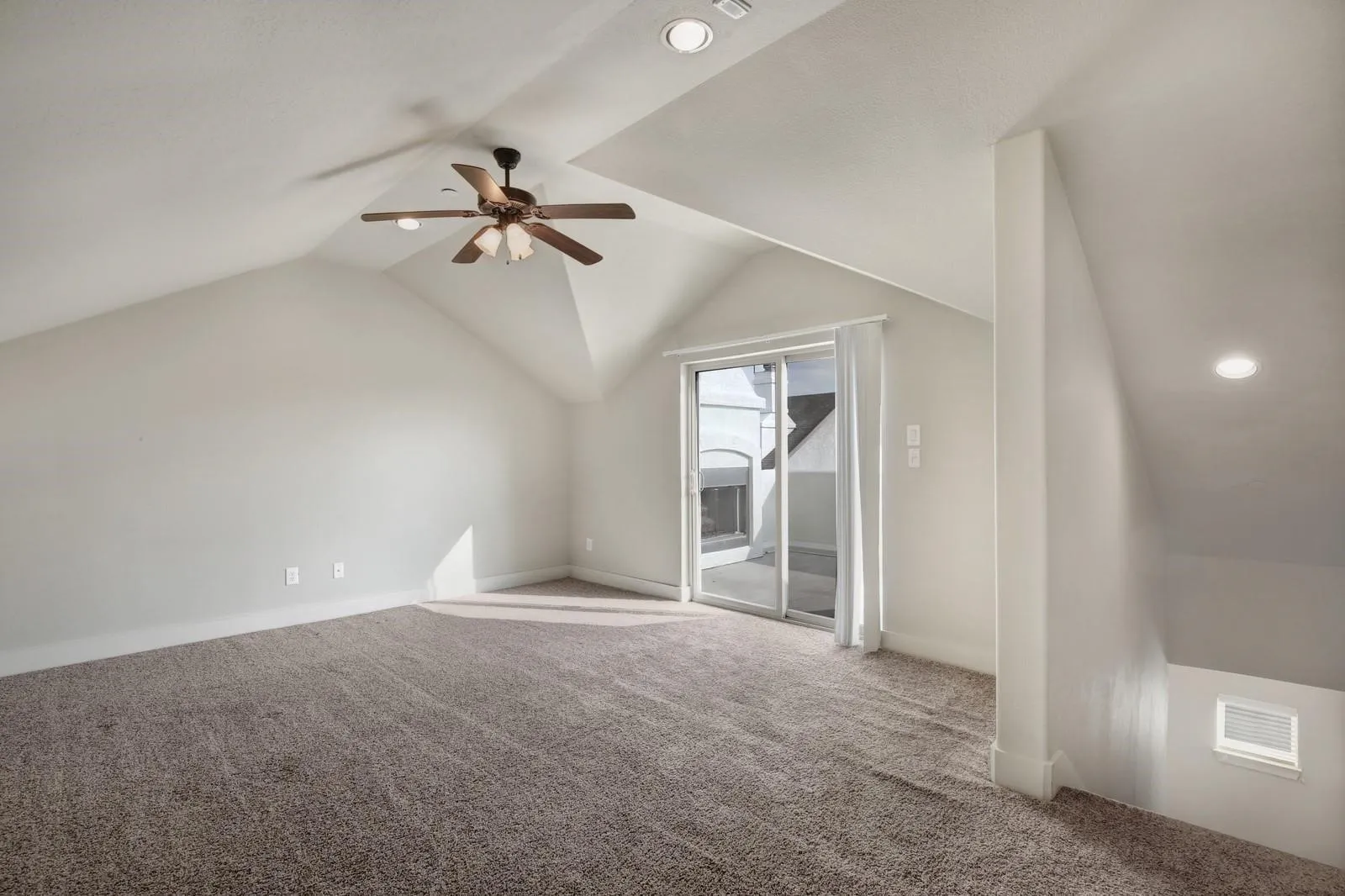 Sloped ceilings with recessed lighting, ceiling fan with wood-finish blades, sliding glass door, and carpeted flooring