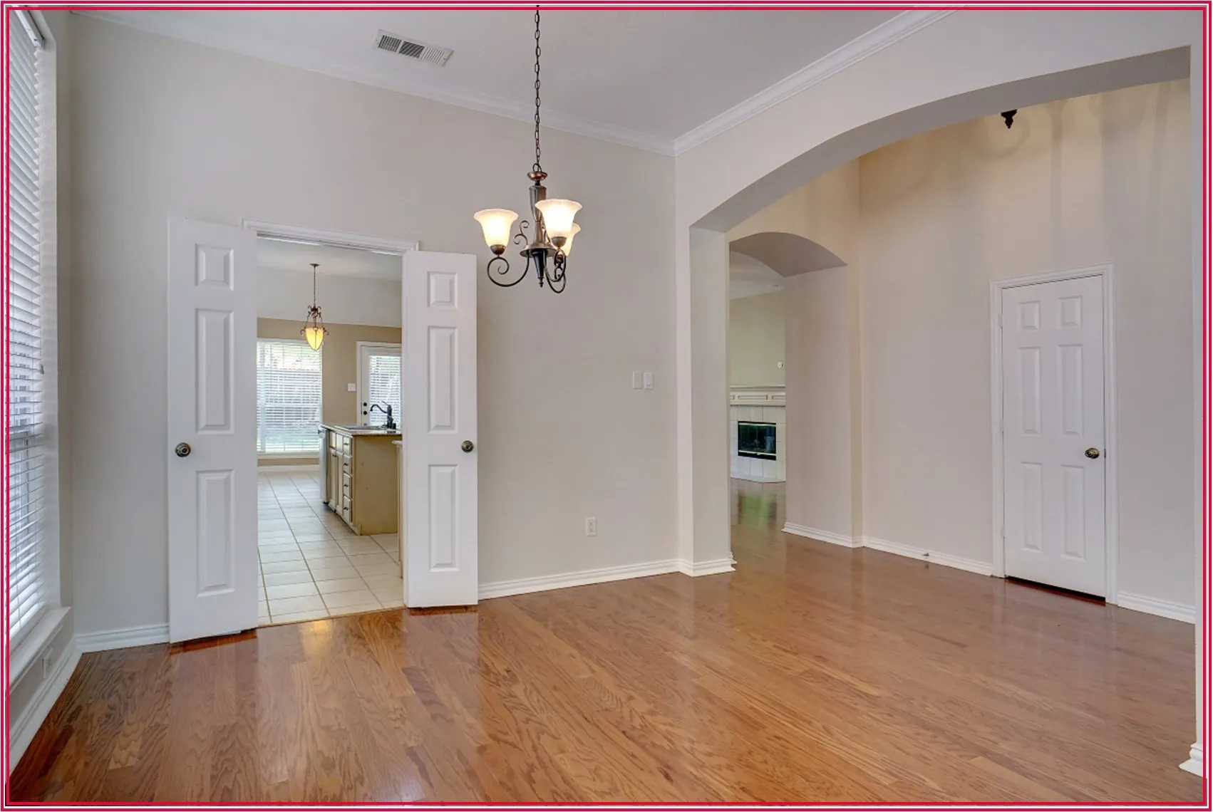 Hardwood flooring, arched doorway, recessed lighting, double doors, and a chandelier