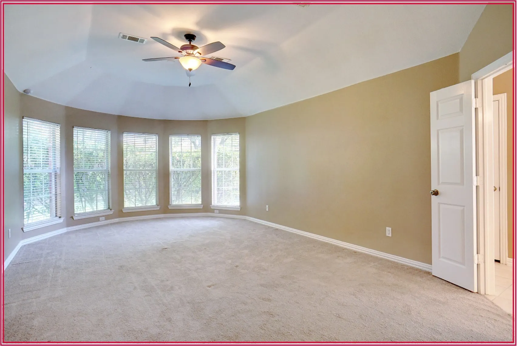 Bay window with five individual windows, neutral carpeting, light-toned wall paint, ceiling fan with integrated lighting, and white interior doors