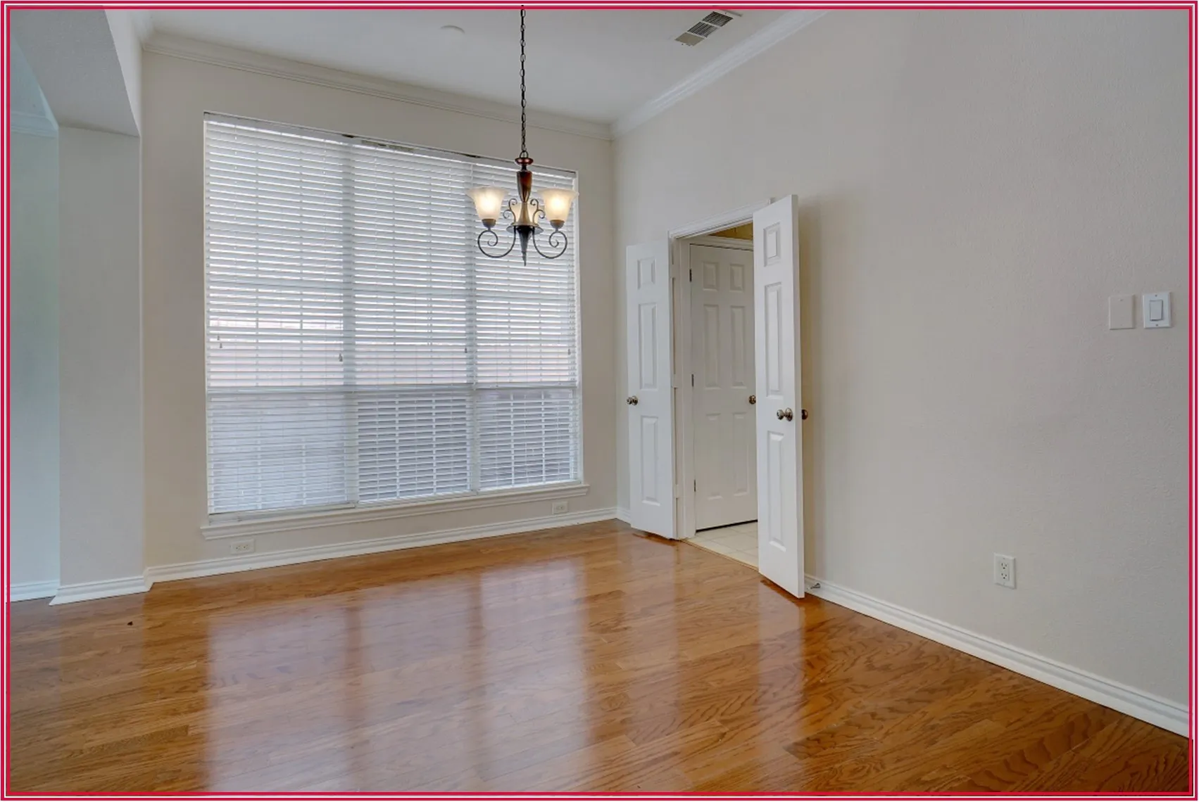 Hardwood flooring, ample natural light, crown molding, double doors, and a chandelier