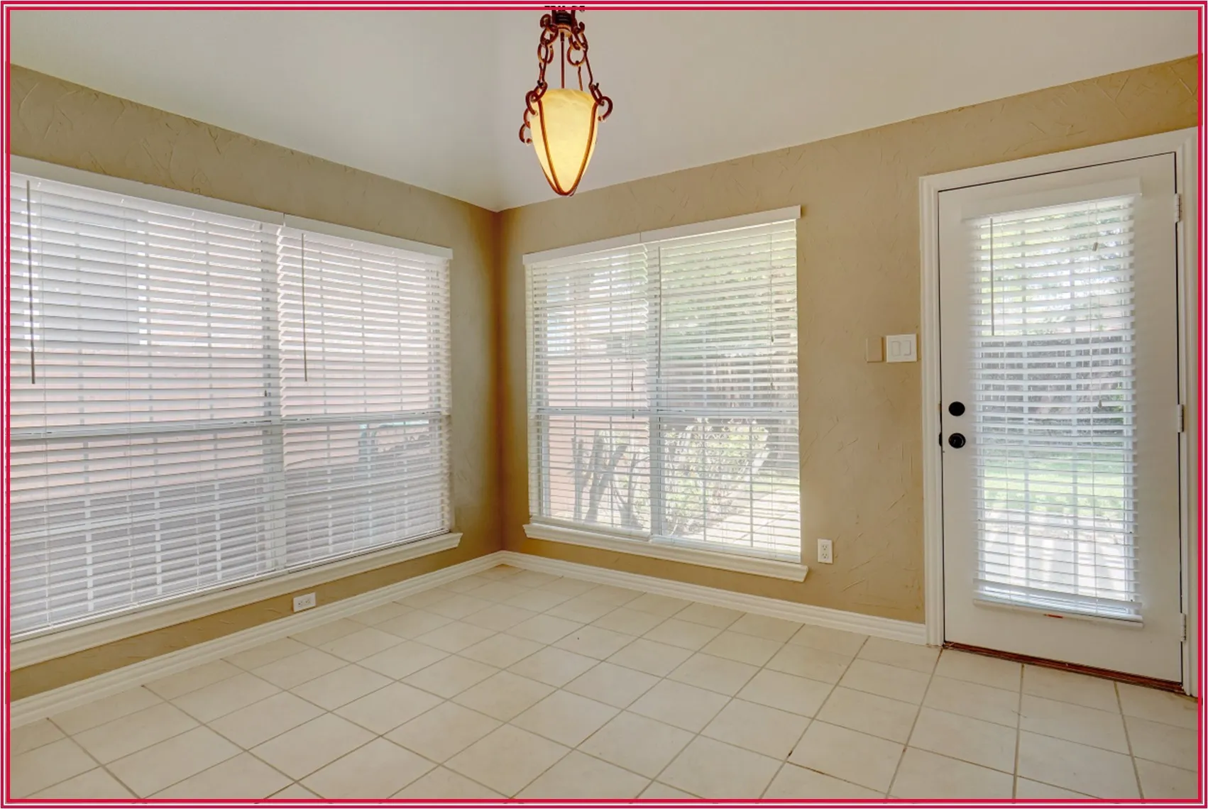 Tile flooring, multiple windows with blinds, a single exterior door, and a decorative ceiling light fixture