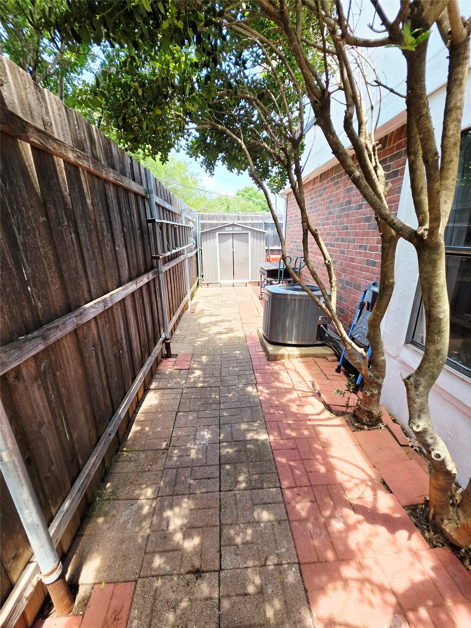 Paved walkway with a wood fence and brick exterior