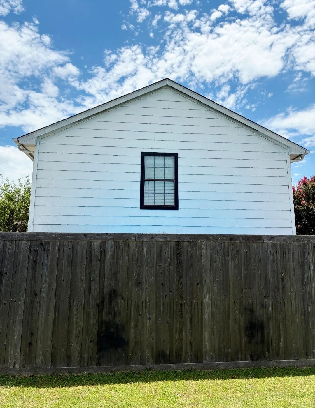Gable roofline with white siding and a black-framed window