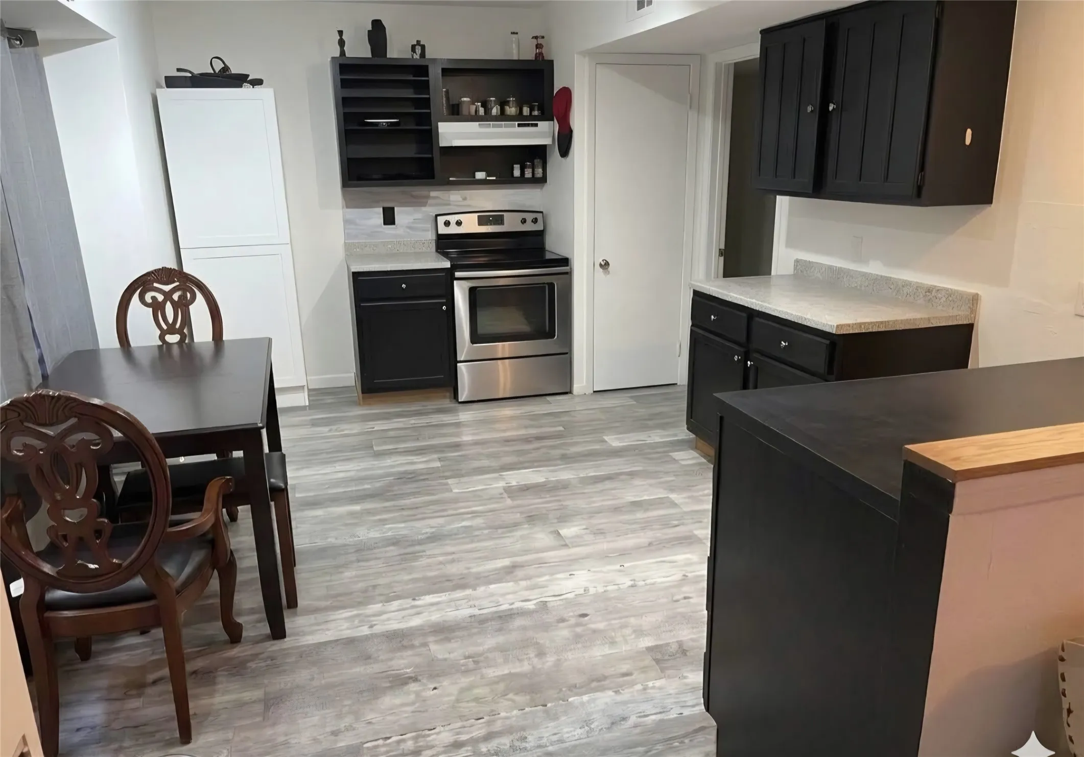 Wood-finish flooring, white countertops, built-in cabinetry, stainless steel range, and tile backsplash