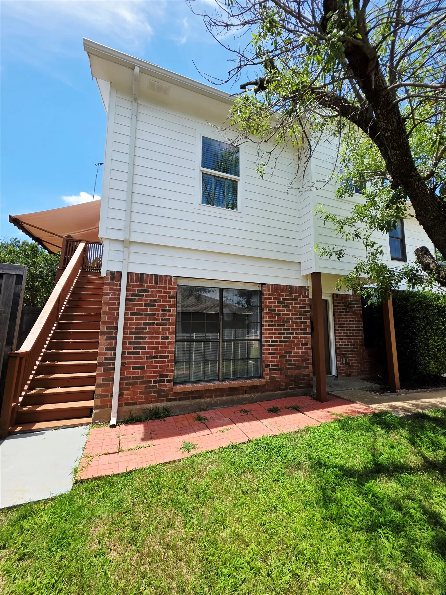 Multi-story exterior with white horizontal siding and brick accents