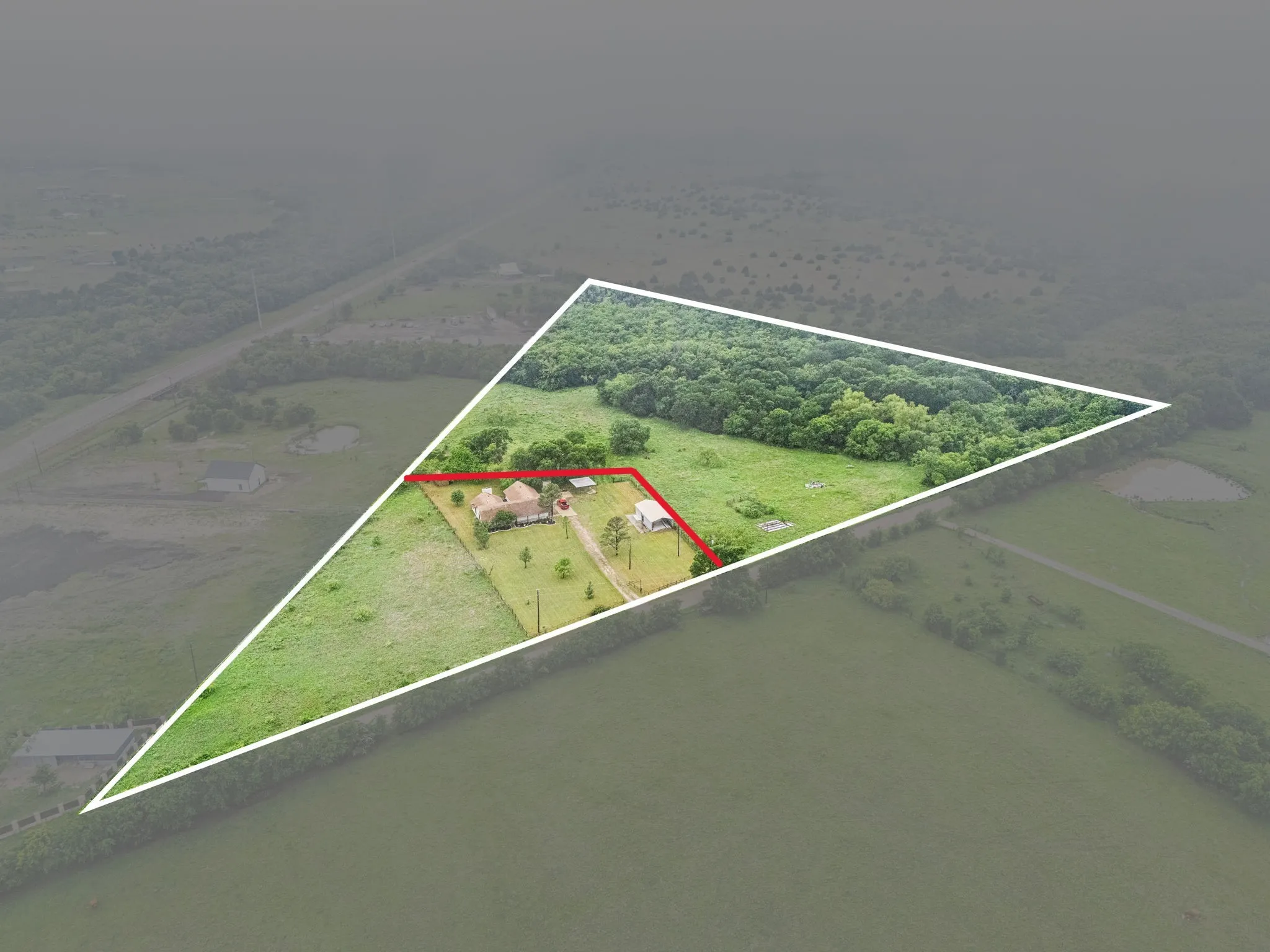 Property featuring a main residence, a detached structure, a tree-lined perimeter, expansive green spaces, and a natural wooded area