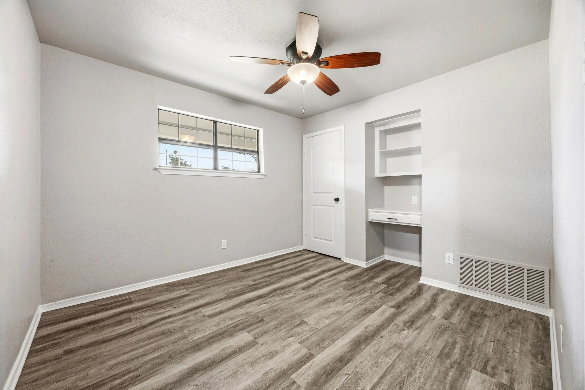 Wood-finish flooring, built-in shelving, built-in desk, ceiling fan, and white trim