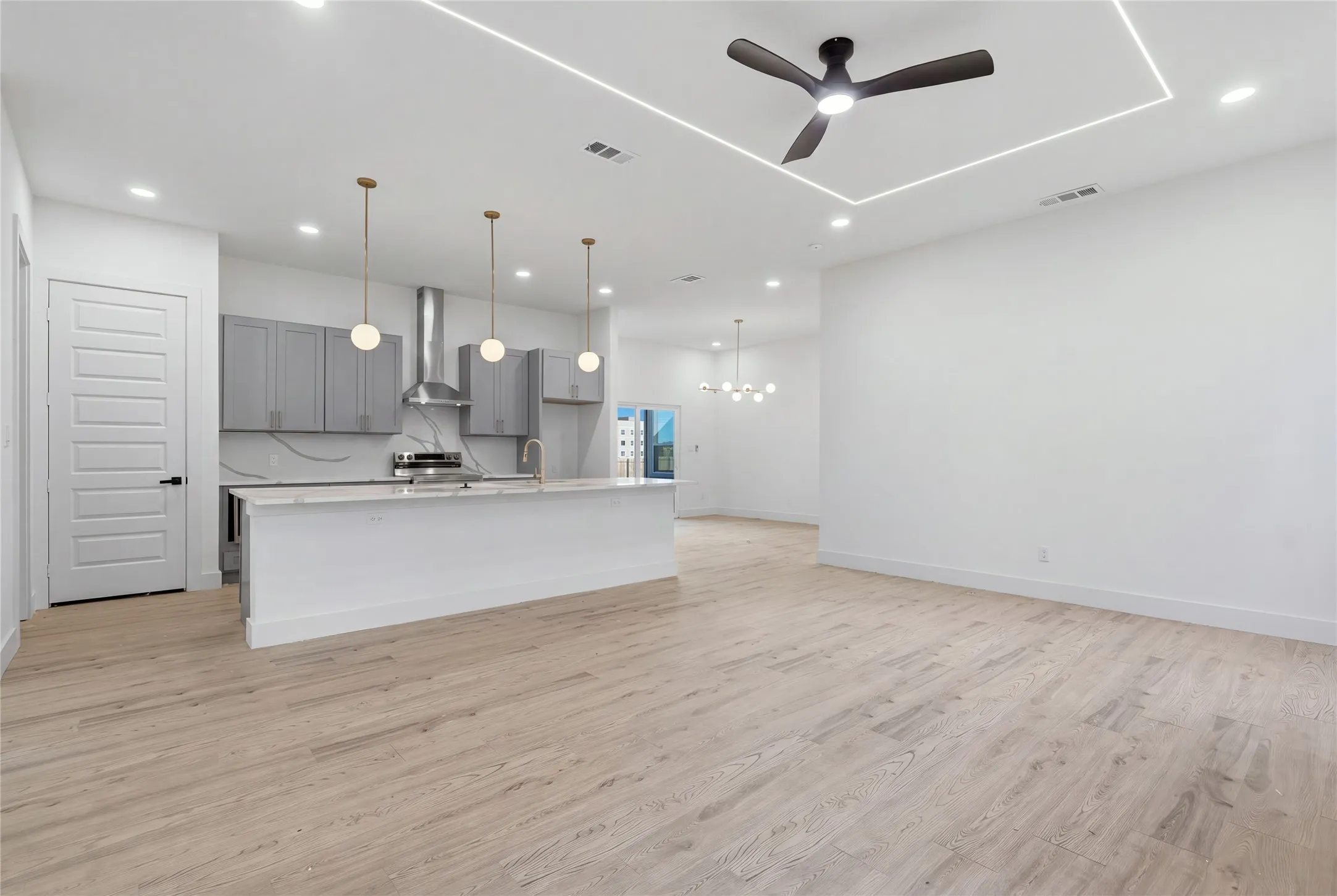 Spacious open-concept living area with light wood-finish flooring