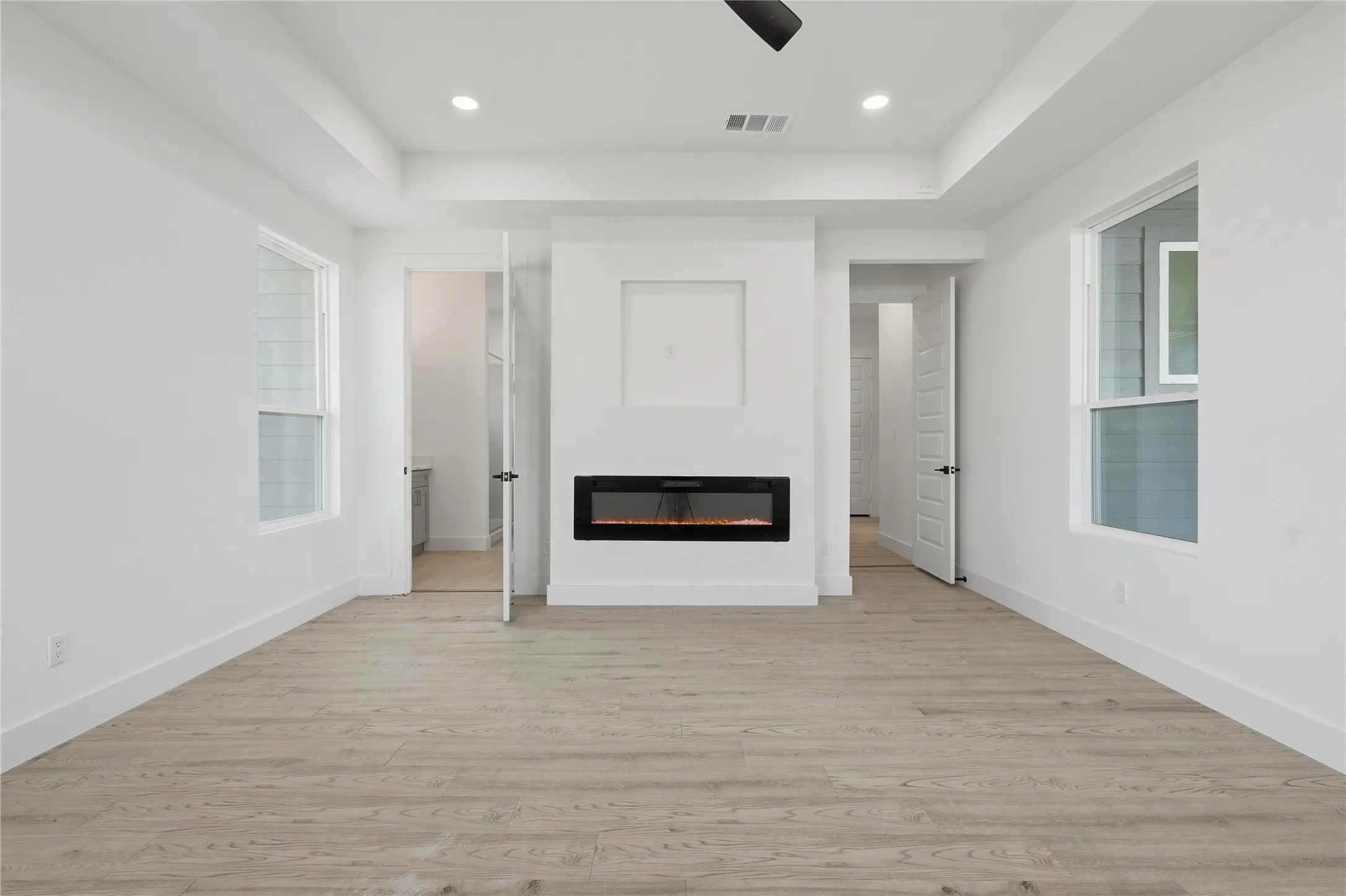 Recessed lighting, tray ceiling, wood-finish flooring, electric fireplace, and white walls