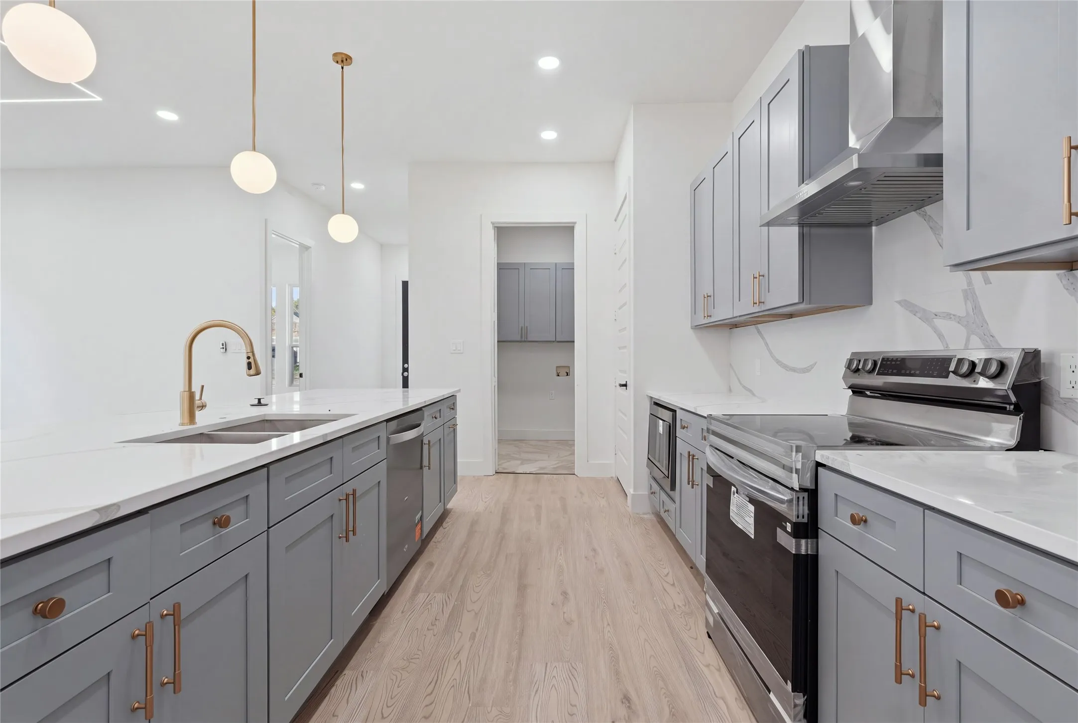 Kitchen featuring light wood-finish flooring, white countertops, gray cabinetry, and stainless steel appliances