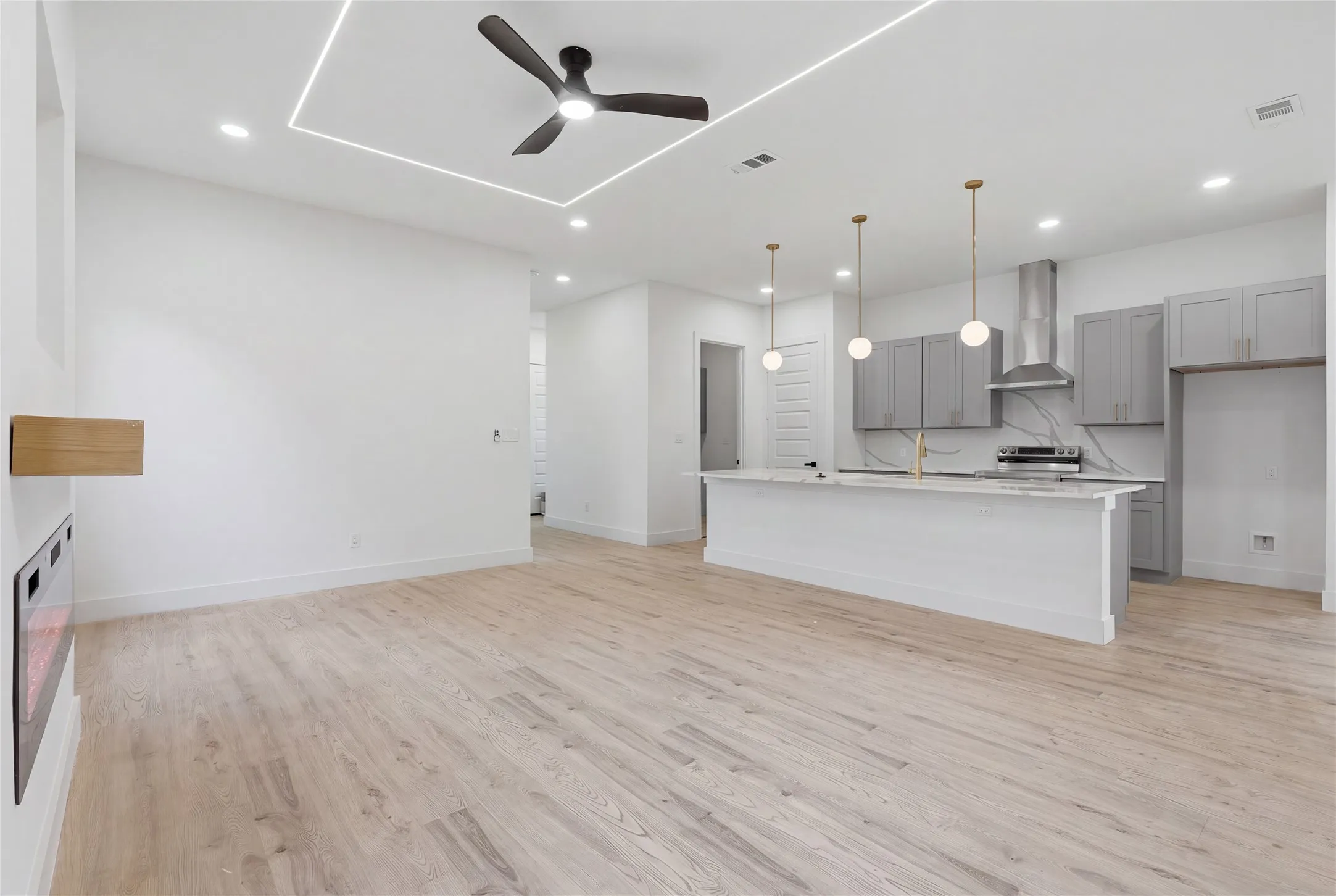 Open-concept living space with light wood-finish flooring, a contemporary ceiling fan, and recessed lighting