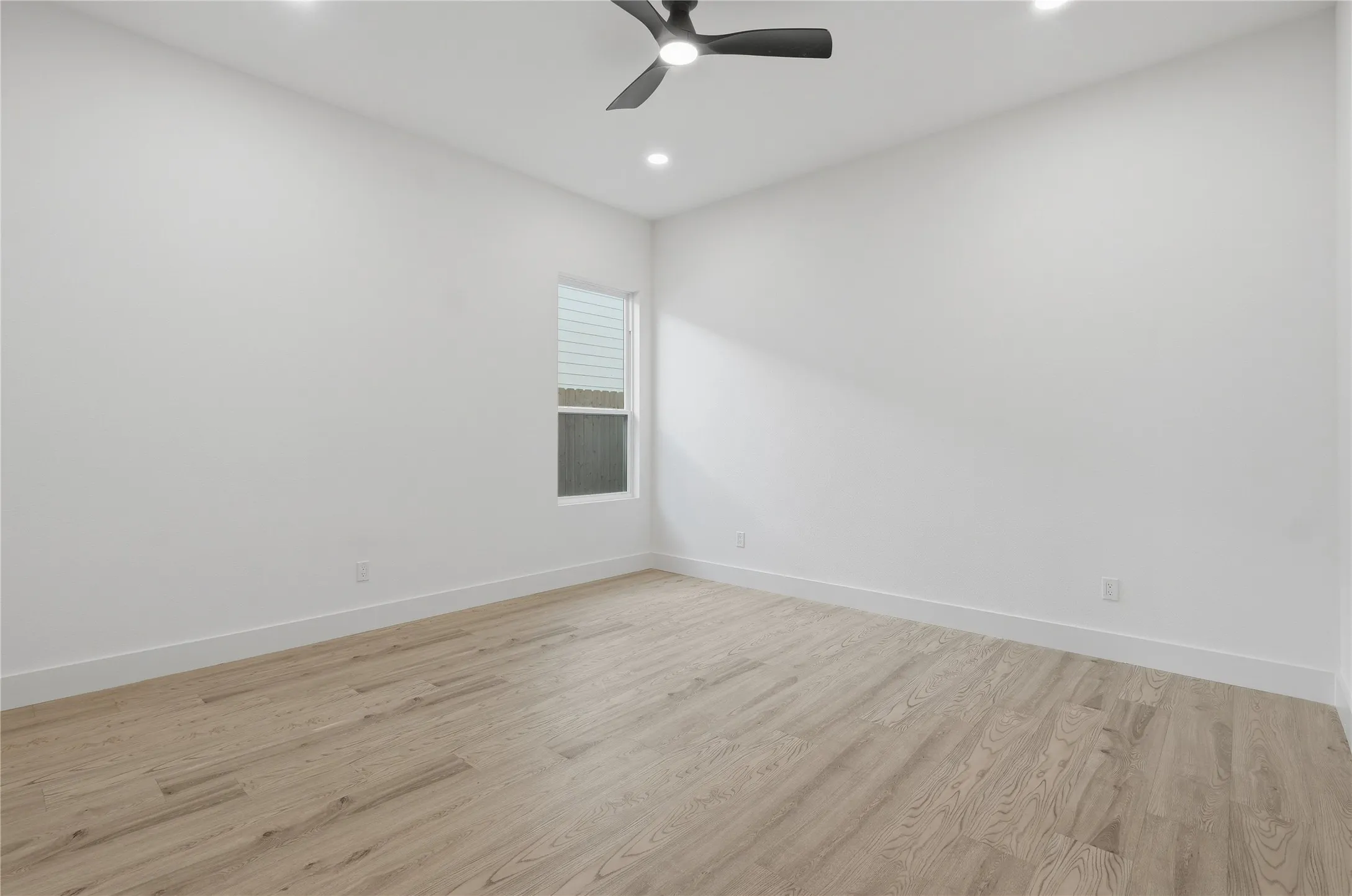 High ceilings with recessed lighting, wood-finish flooring, a contemporary ceiling fan, and a single window