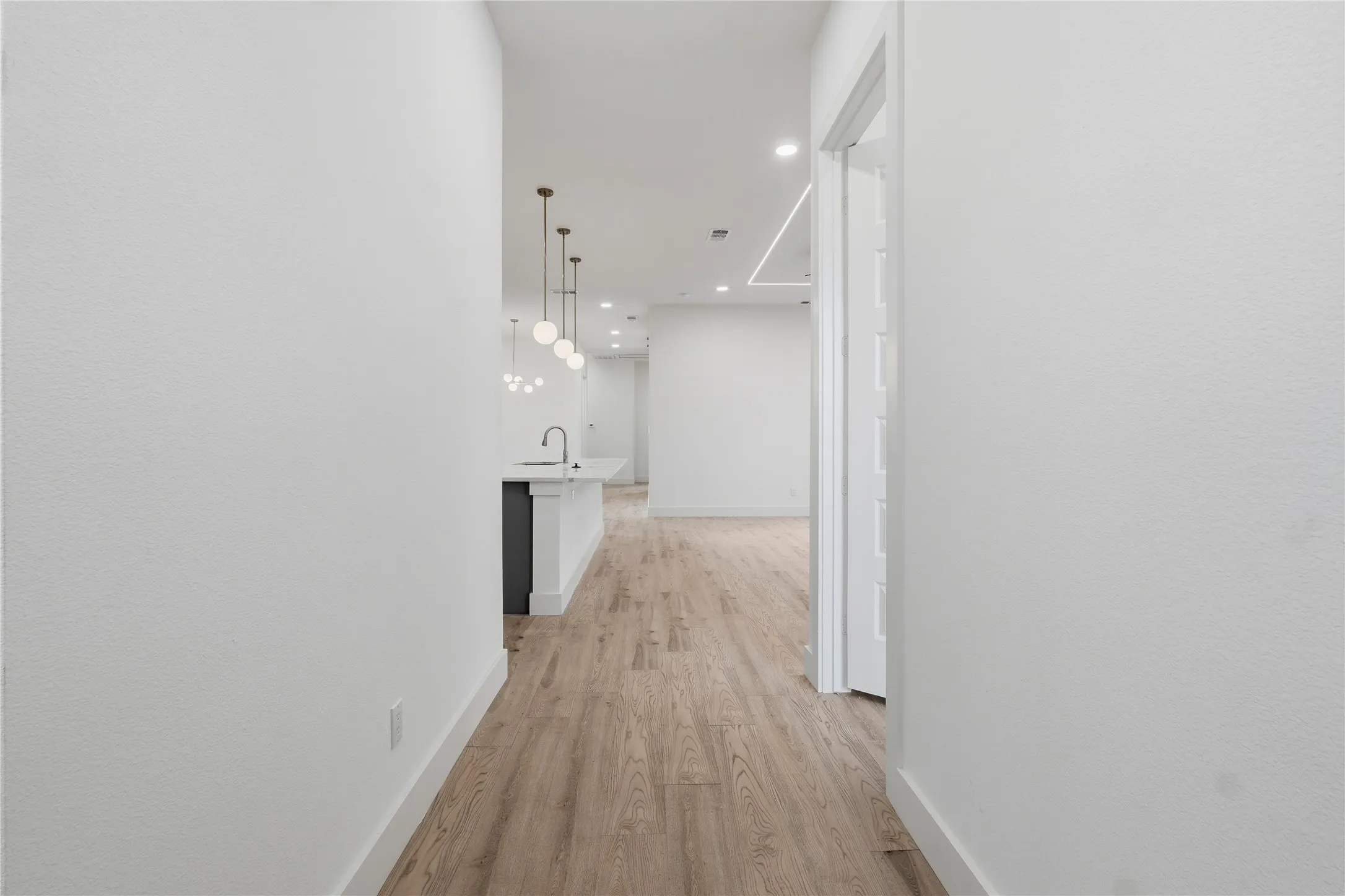 Wood-finish flooring throughout, with a kitchen island featuring a sink and a gooseneck faucet