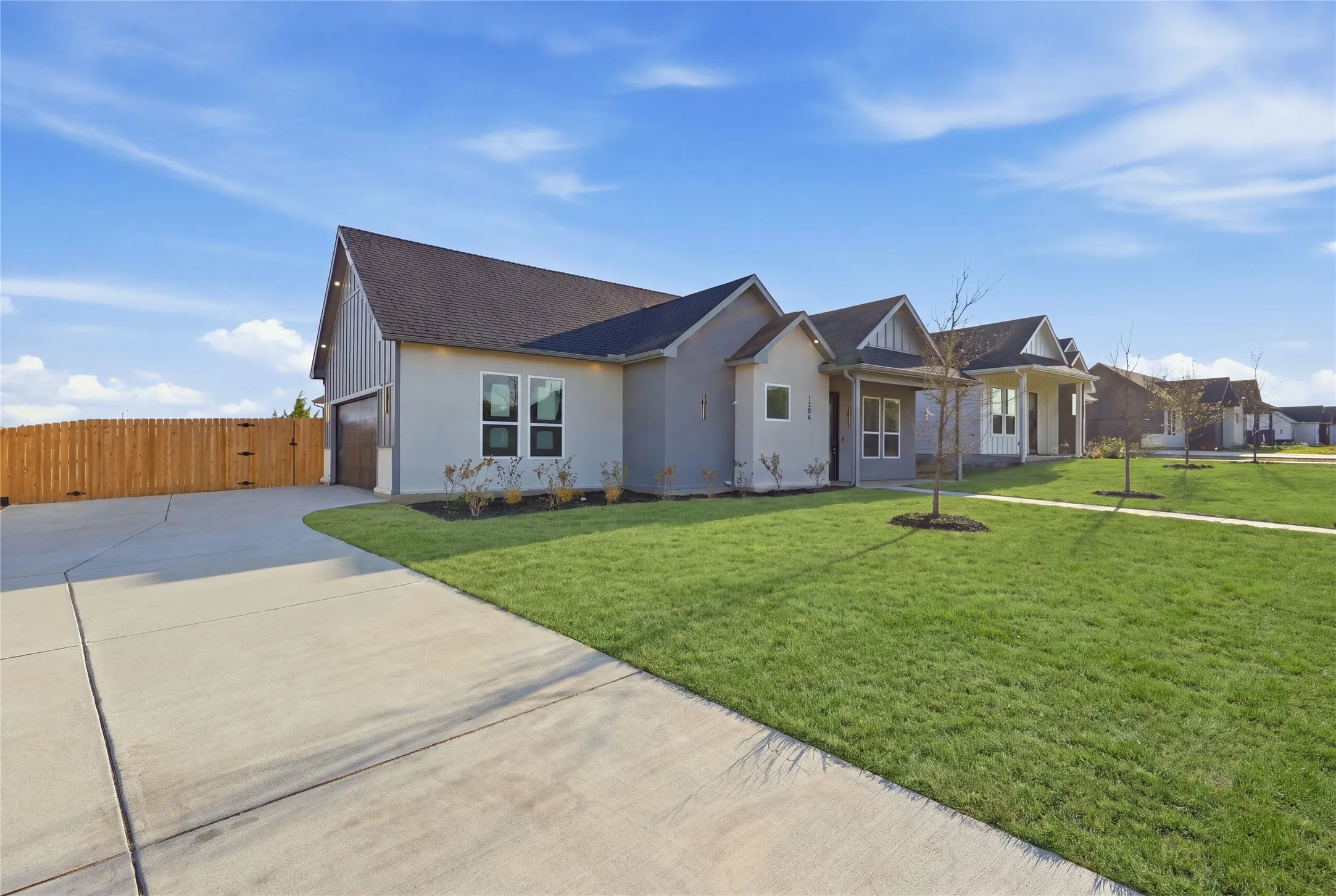 Contemporary exterior with a dark-pitched roof, light-colored siding, and a two-car garage