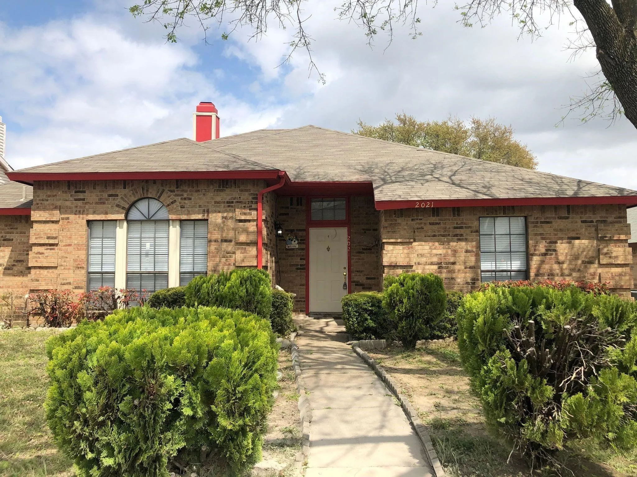 Brick exterior with a prominent arched window, red roof trim, and a red chimney accent