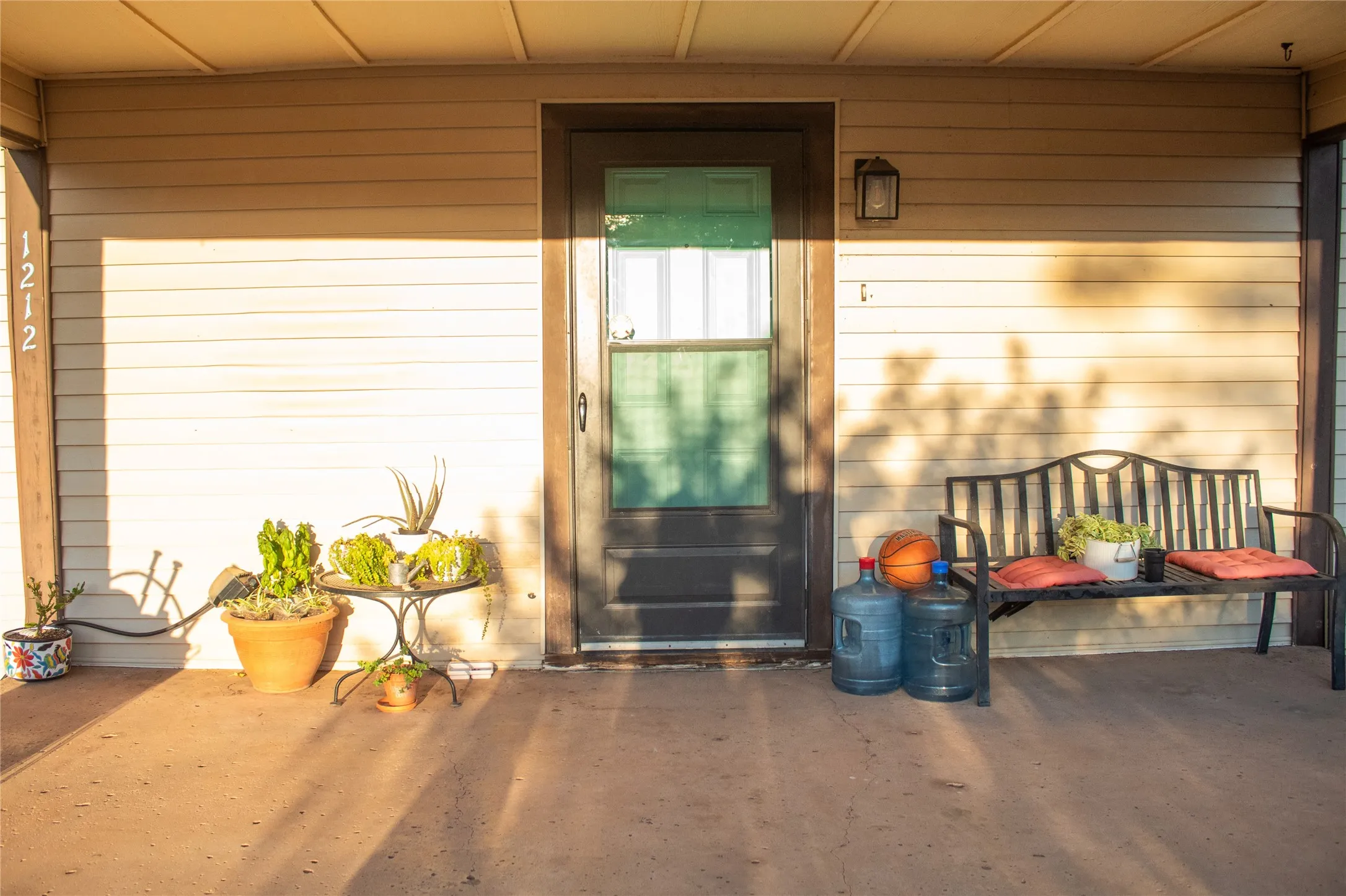 Covered porch with concrete flooring, horizontal siding, and an exterior light fixture