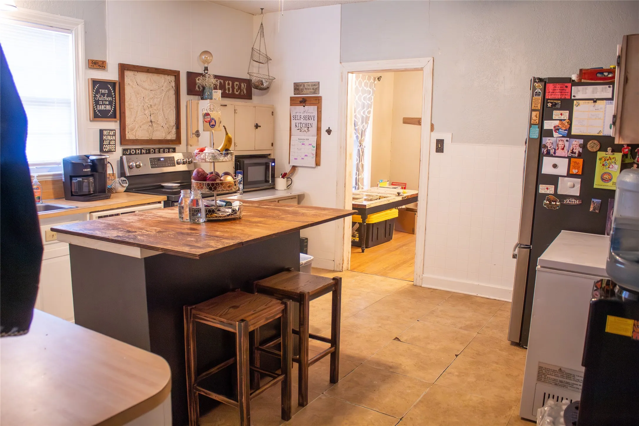 Hardwood island with seating, wood-finish countertops, stainless steel range, and built-in upper cabinetry