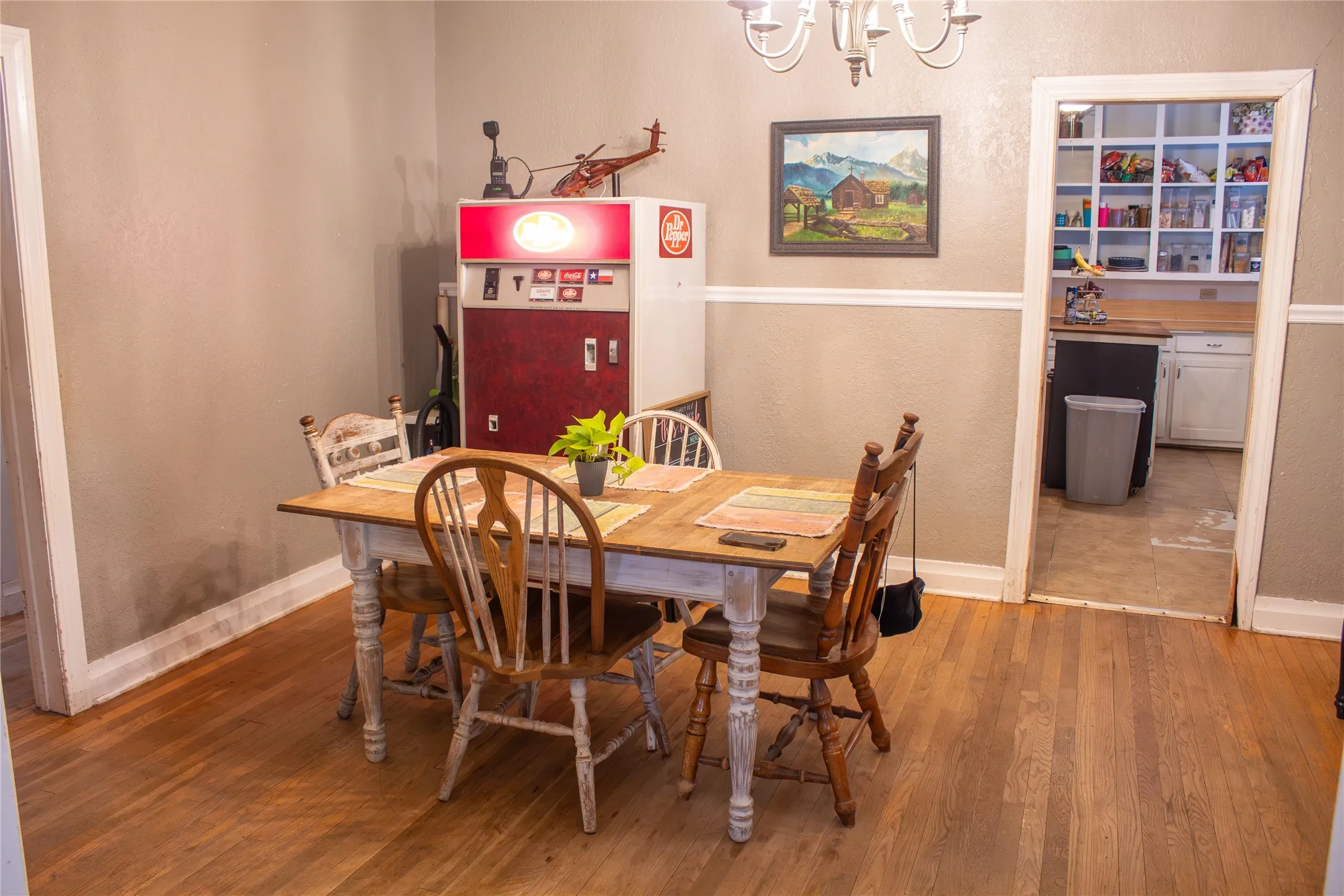 Hardwood flooring, neutral wall color, white trim, and a decorative chandelier