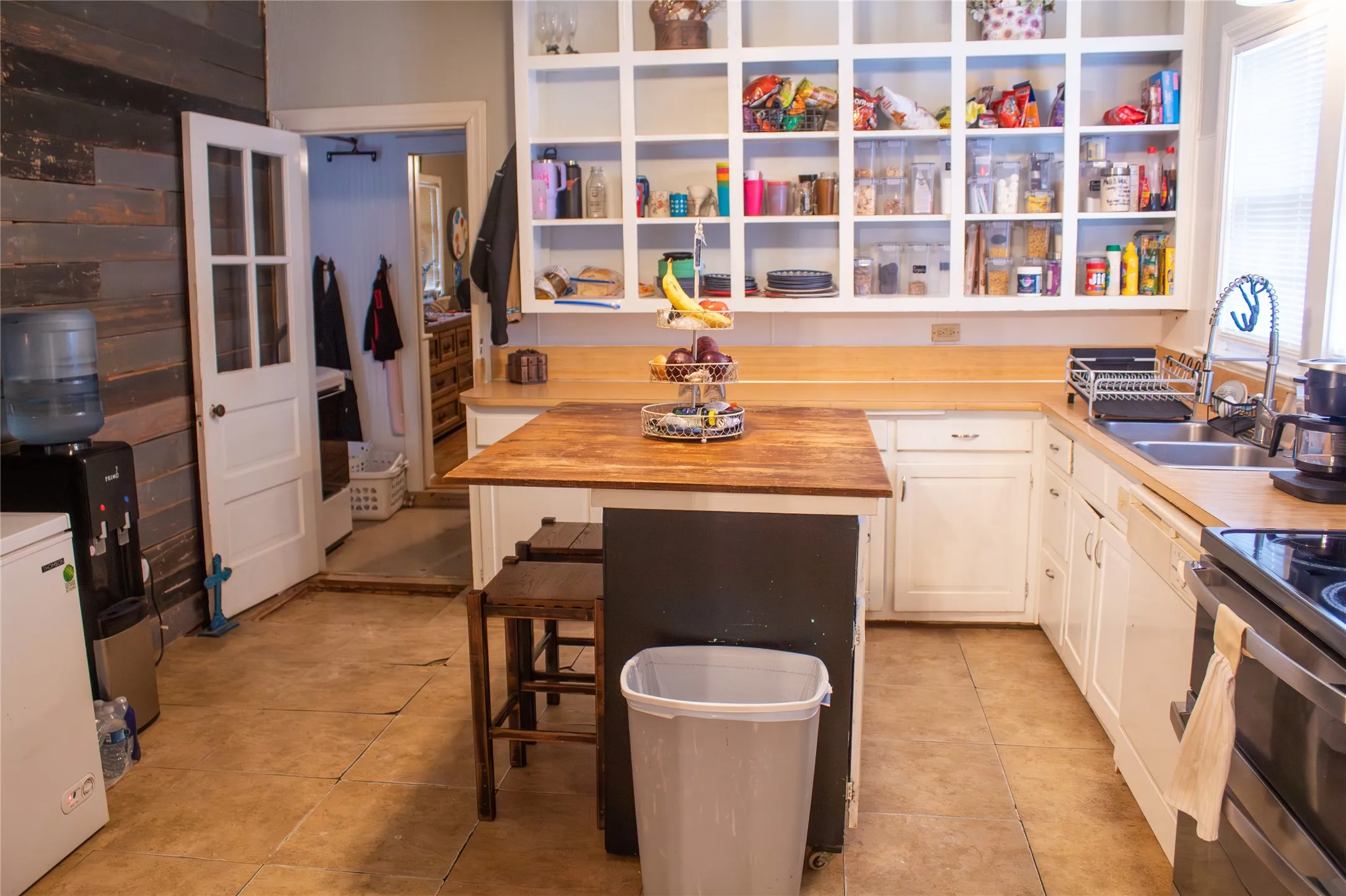 Built-in open shelving, wood countertops, and white cabinetry