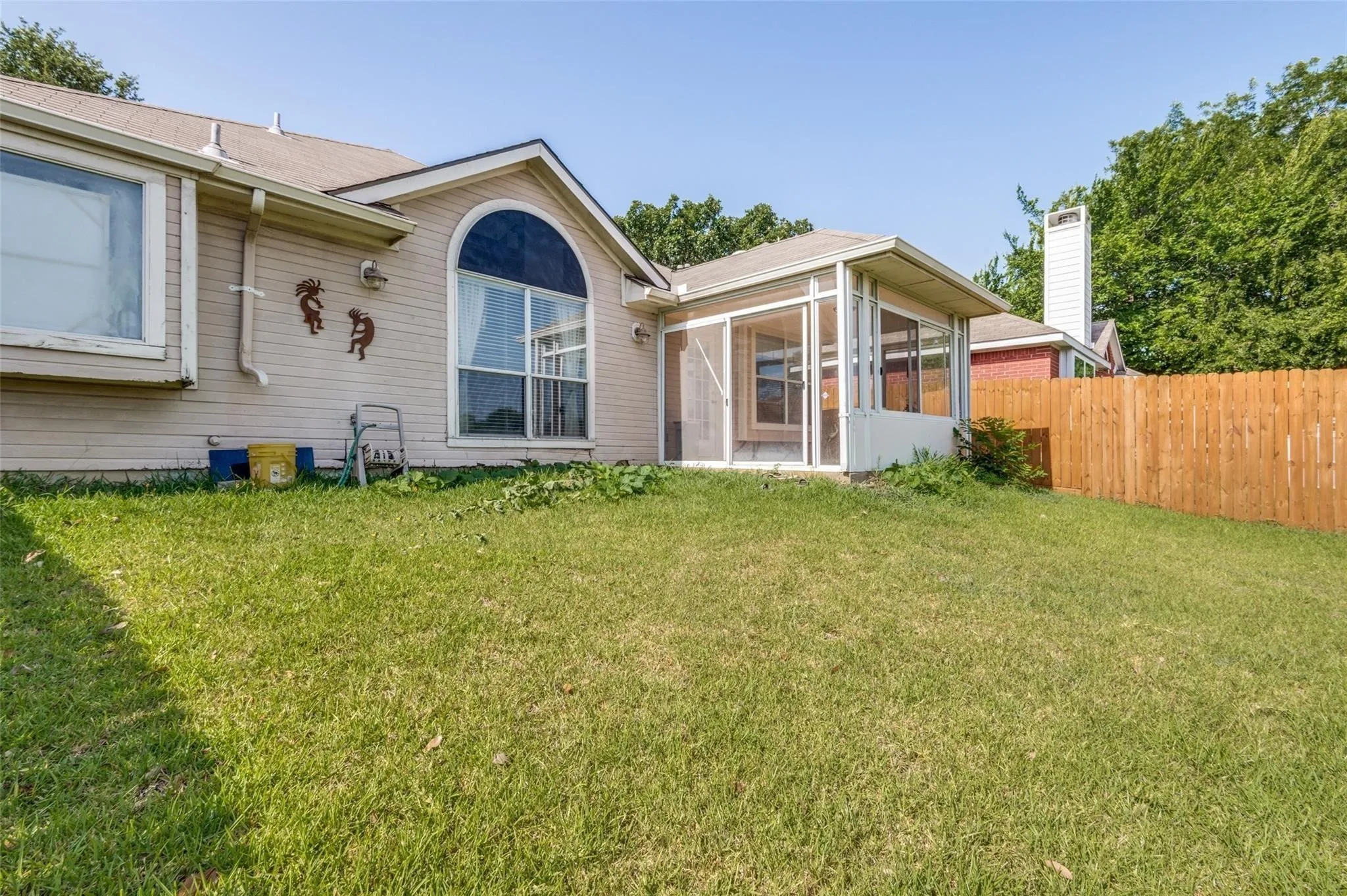 Expansive rear yard with a wood fence, screened-in porch, and a large arched window feature