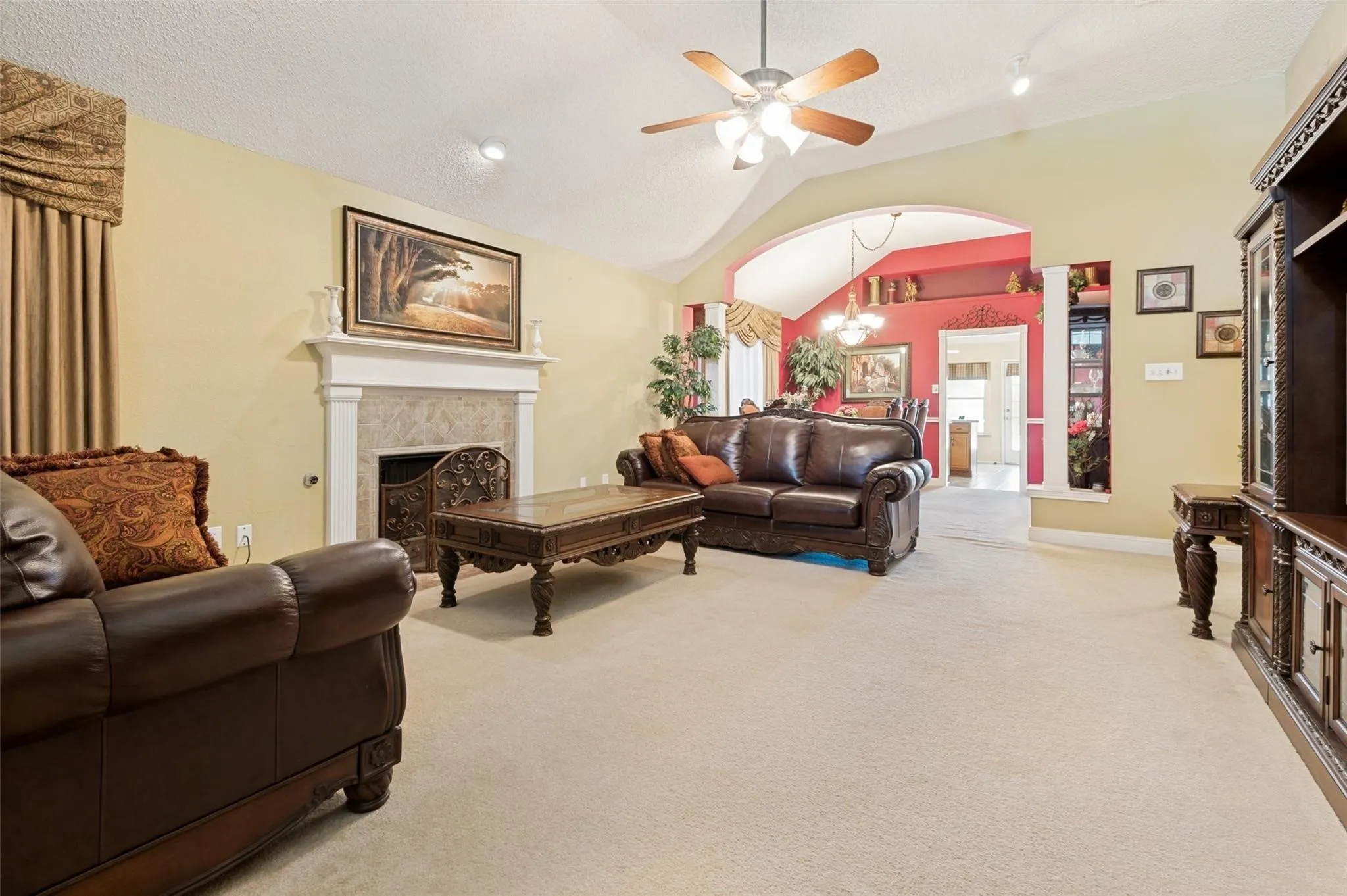 Vaulted ceiling with a ceiling fan, recessed lighting, and a decorative fireplace with a stone surround