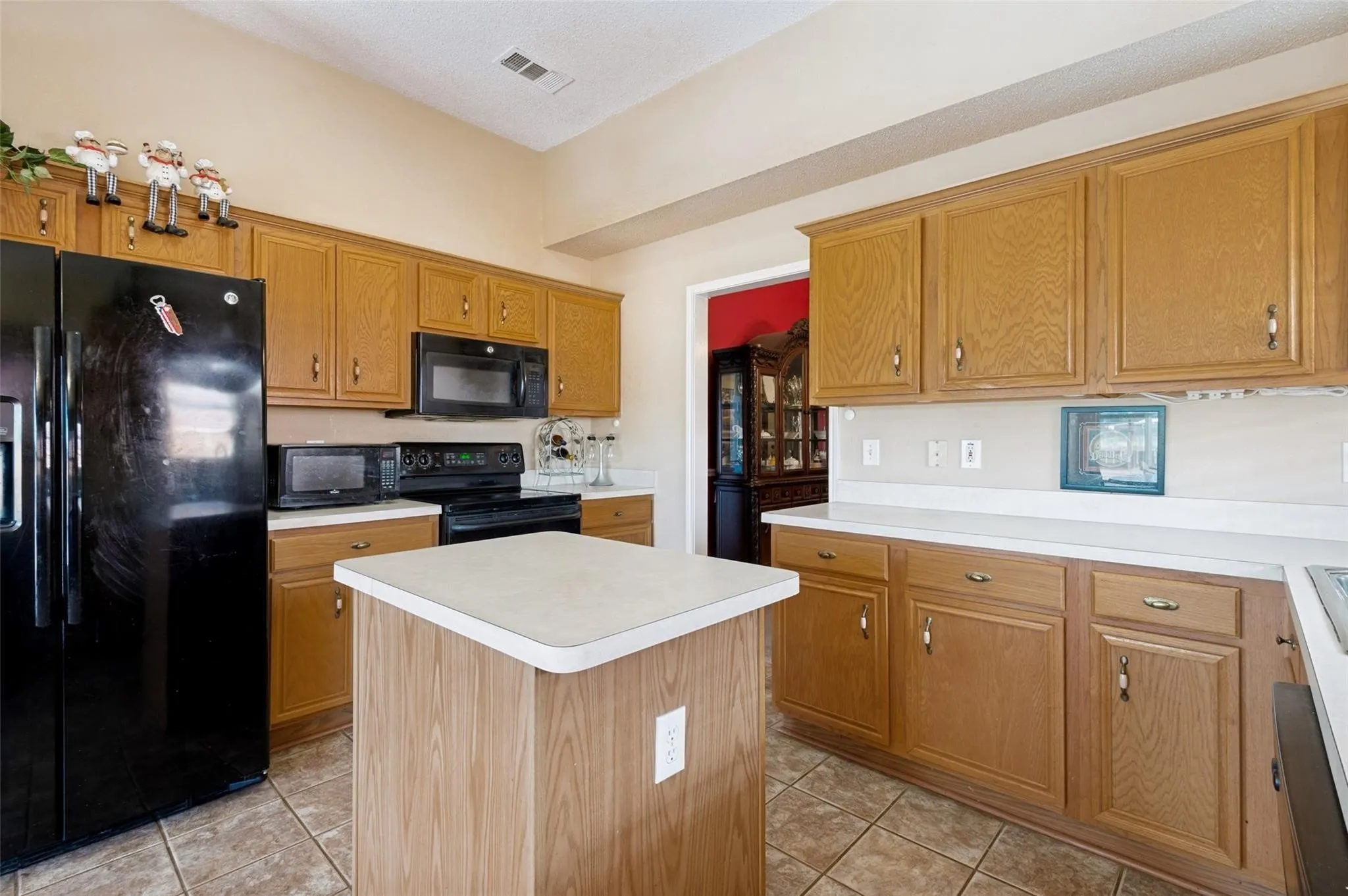 Kitchen featuring wood cabinetry, white countertops, a central island, and black appliances