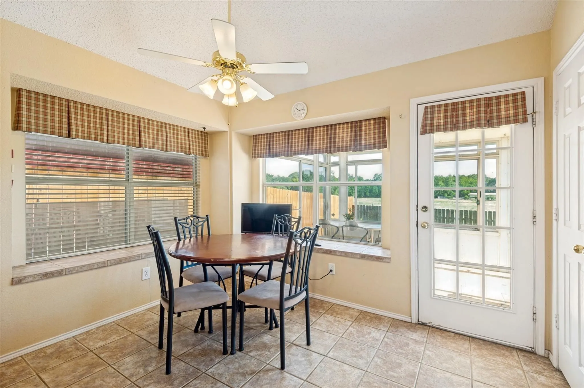 Tiled flooring, multiple windows with blinds, built-in window sills, and a ceiling fan with integrated lighting