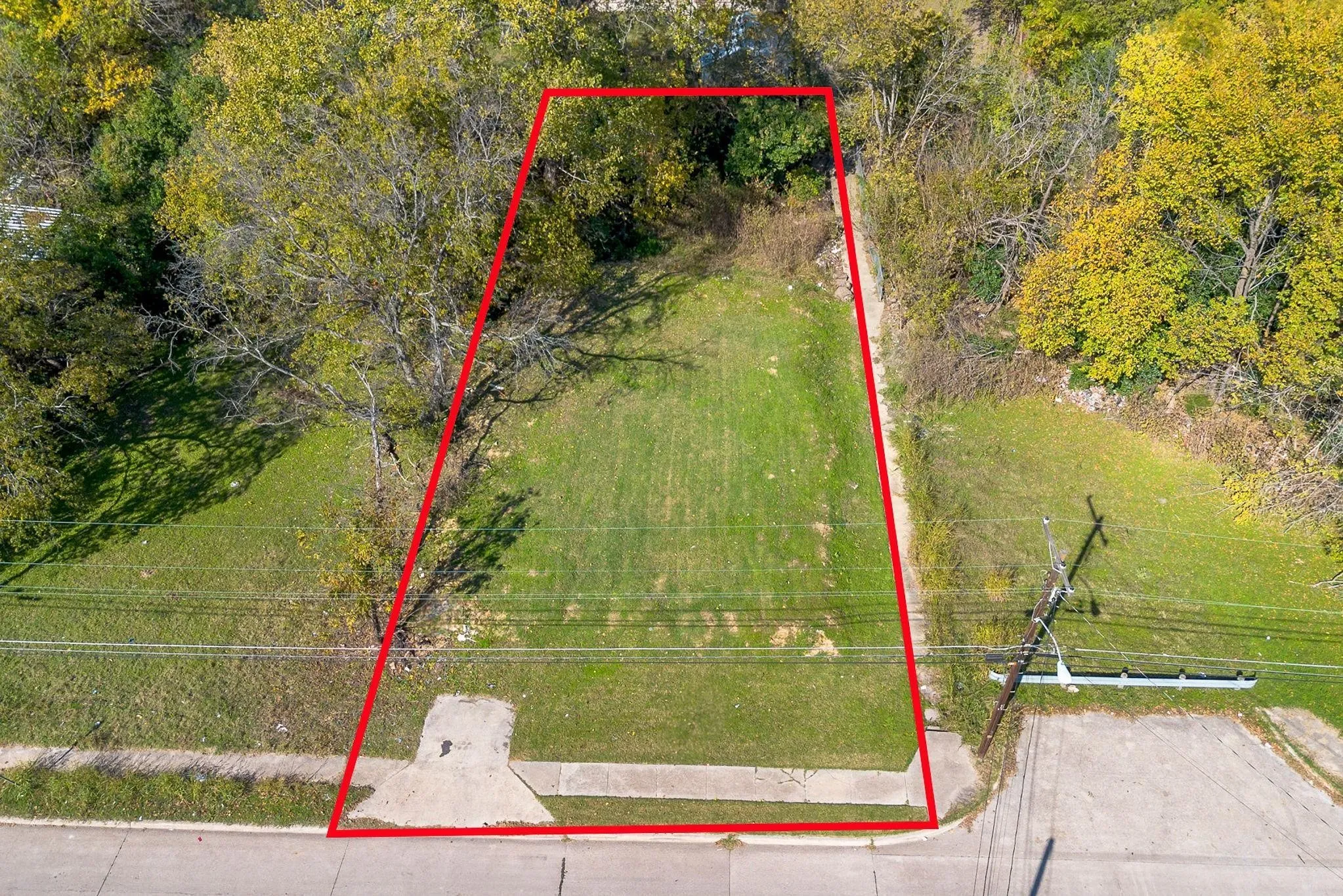 Expansive grass lot with mature trees and paved street frontage