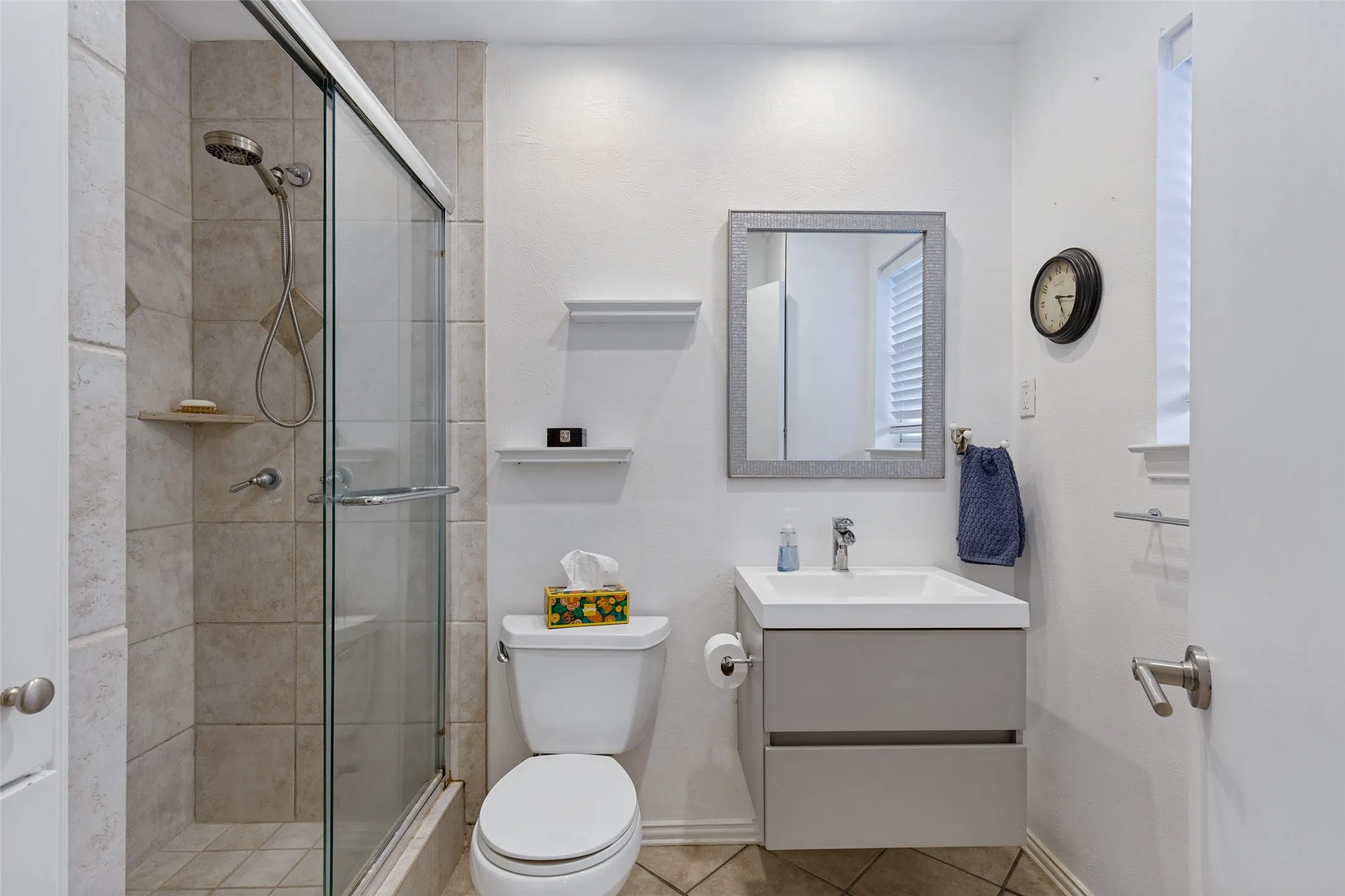 Glass-enclosed shower with tiled walls and showerhead
