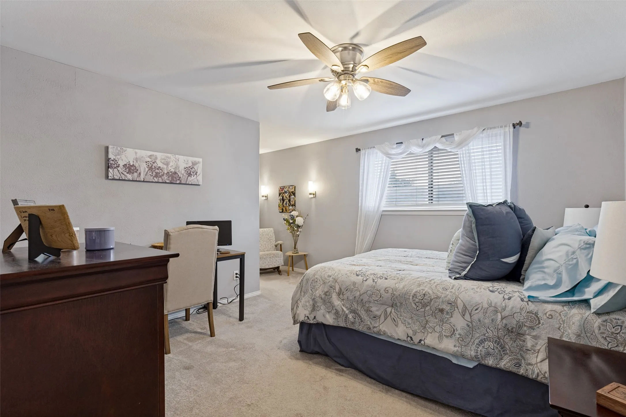 Carpeted flooring, a ceiling fan with integrated lighting, and a window with blinds and sheer curtains